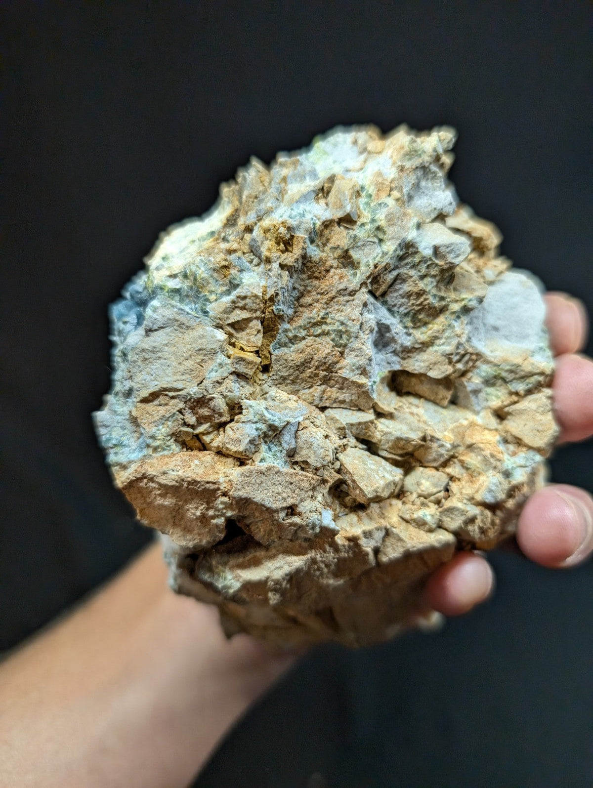 A rugged, irregularly shaped mineral specimen with a mix of earthy brown and pale blue-green hues.