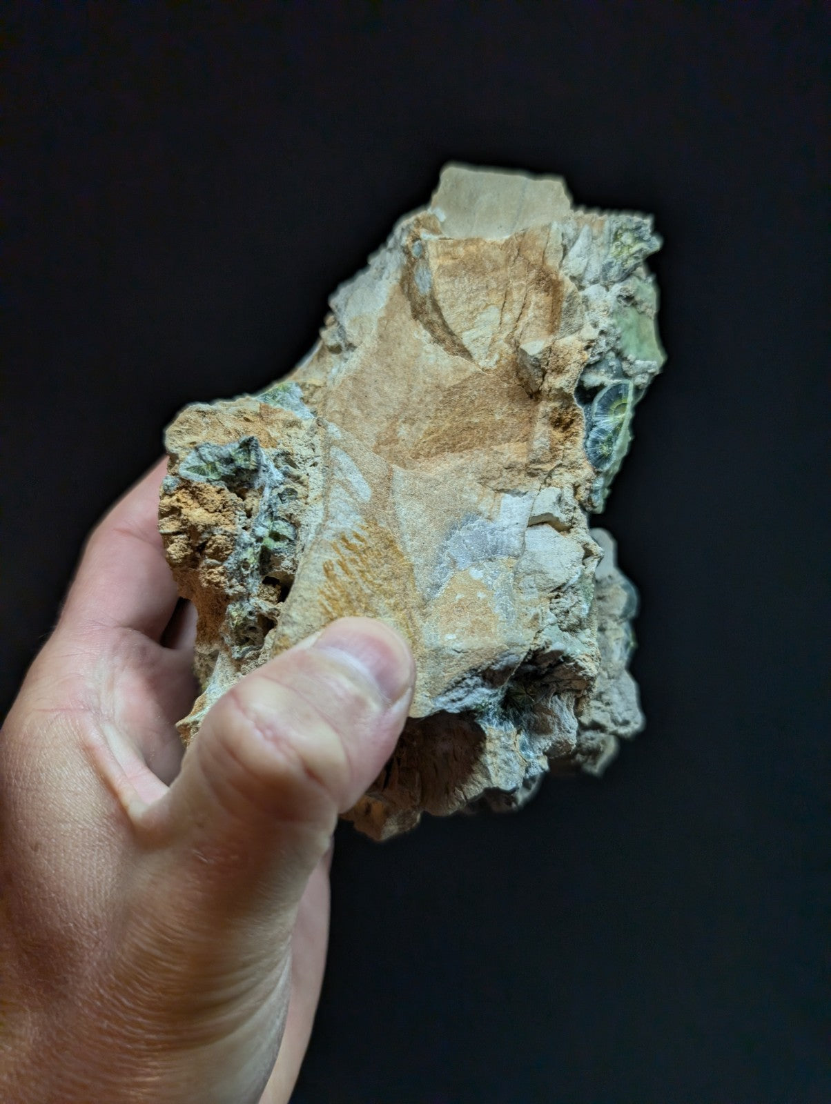A rugged, irregularly shaped mineral specimen with a mix of earthy brown and muted green hues, showcasing natural textures and layered formations.