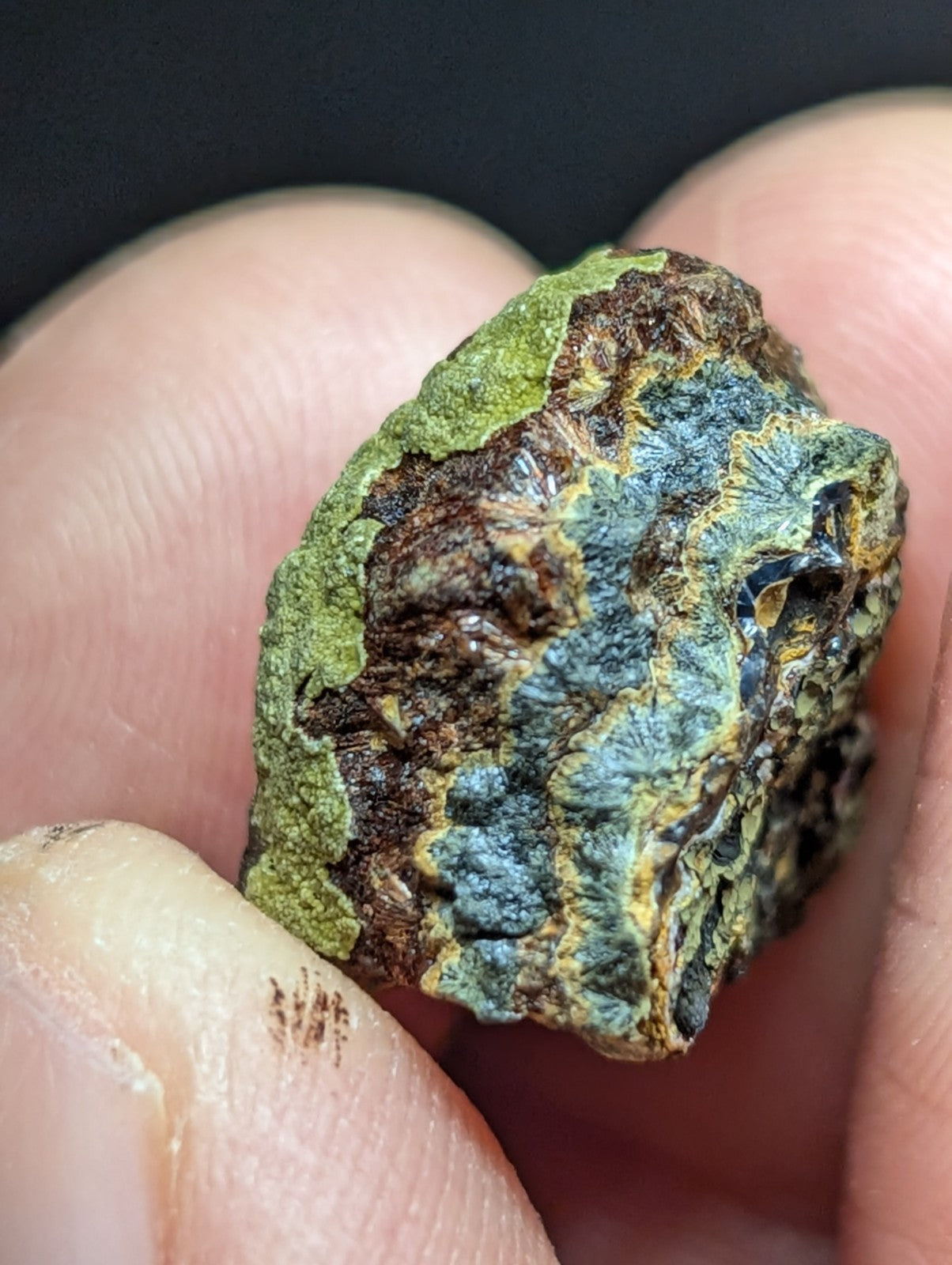 A rugged, irregularly shaped mineral specimen with a textured surface displaying patches of green, blue-gray, and brown.