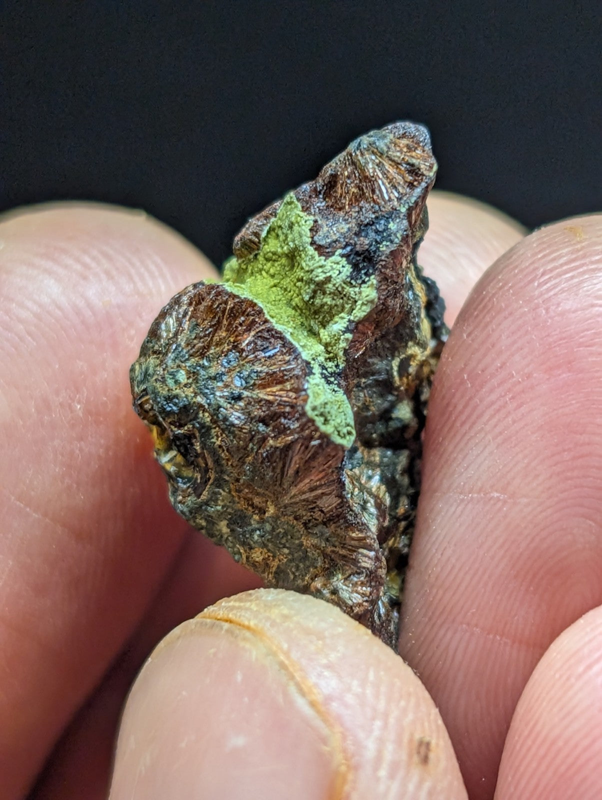 A rugged, irregularly shaped mineral specimen with a dark brown base and vibrant green patina covering parts of its surface.