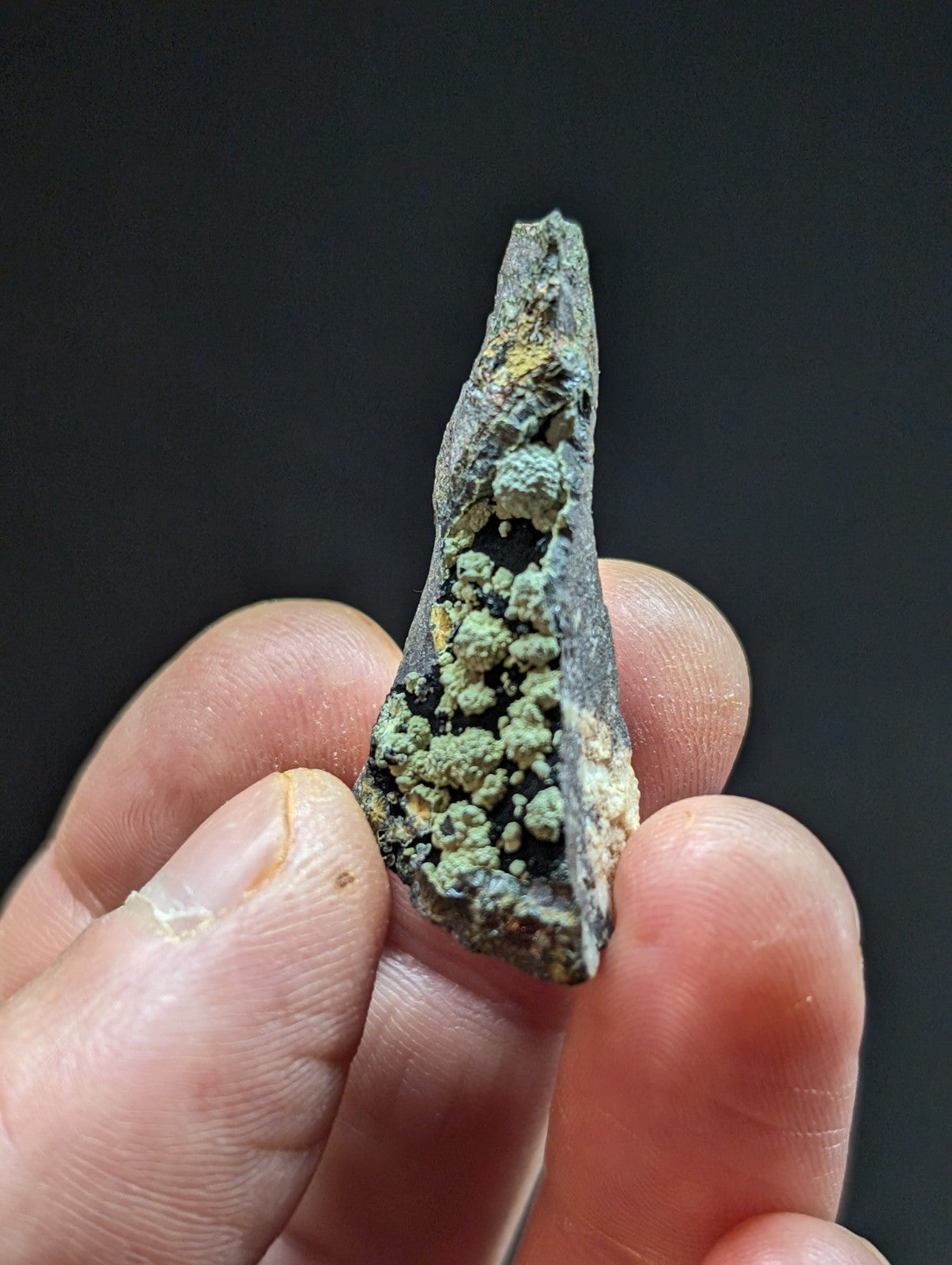 A weathered, pointed bronze artifact with patches of green patina and yellow corrosion.