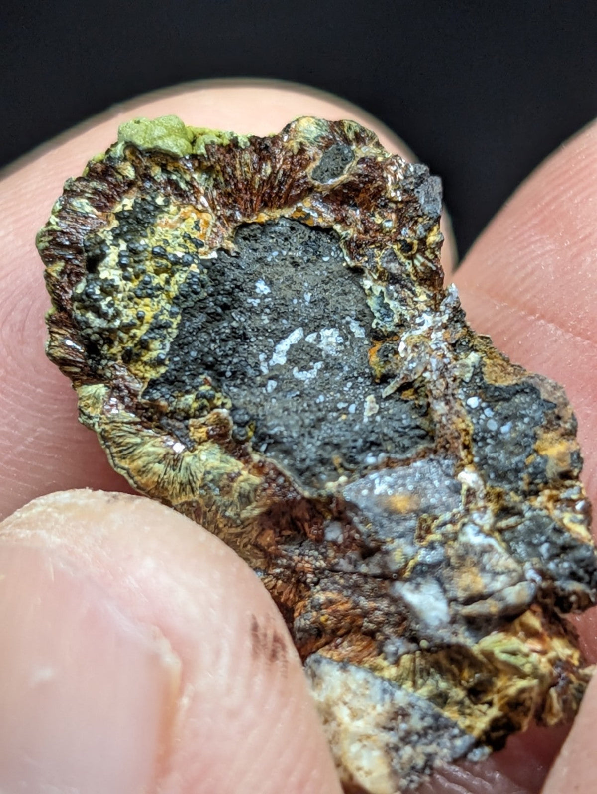 A rugged, irregularly shaped mineral specimen with a dark gray core surrounded by patches of green and brown patina.