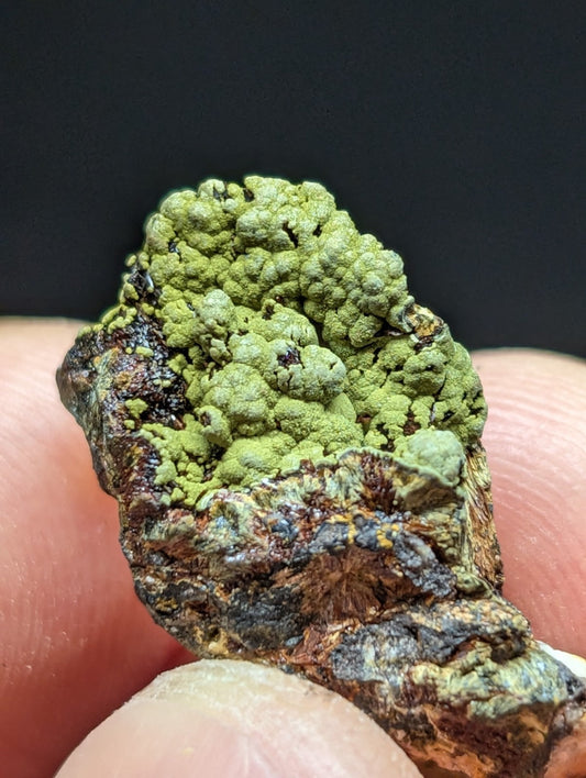 A textured, mossy green mineral specimen with a rough, earthy base.