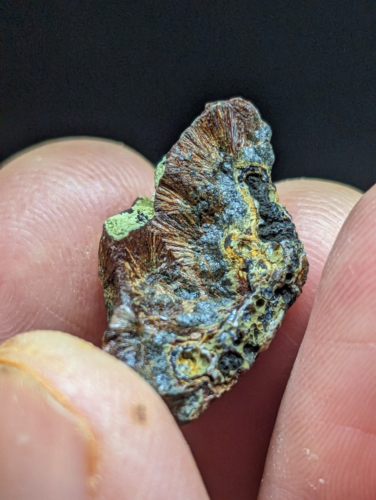 A weathered, irregularly shaped mineral specimen with a textured surface displaying patches of green patina, blue-green hues, and brownish tones.