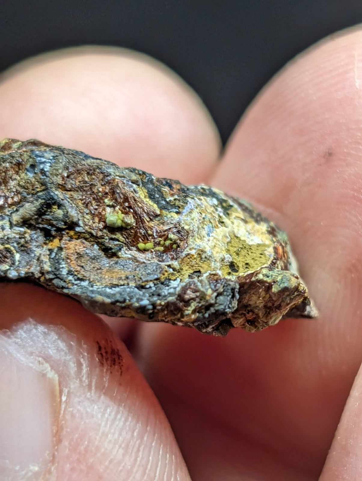 A rugged, irregularly shaped mineral specimen with a mottled surface of greenish-yellow and bluish-gray patina.