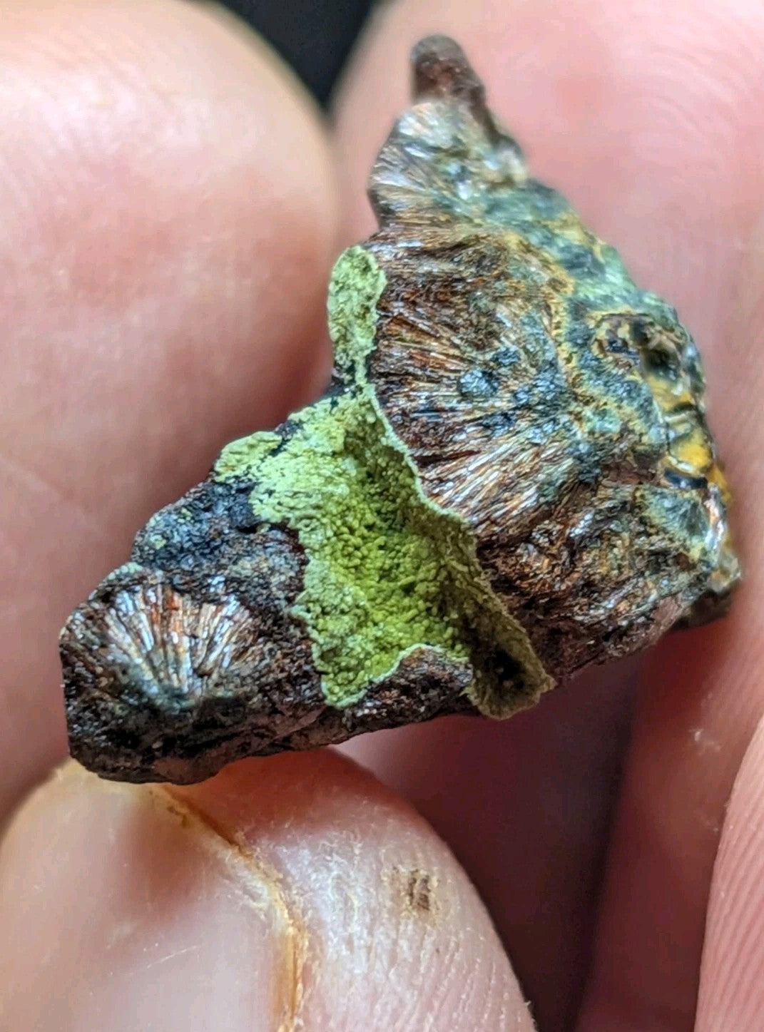 A rugged, irregularly shaped mineral specimen with a textured surface featuring patches of vibrant green lichen and areas of dark brown and blue-green patina.