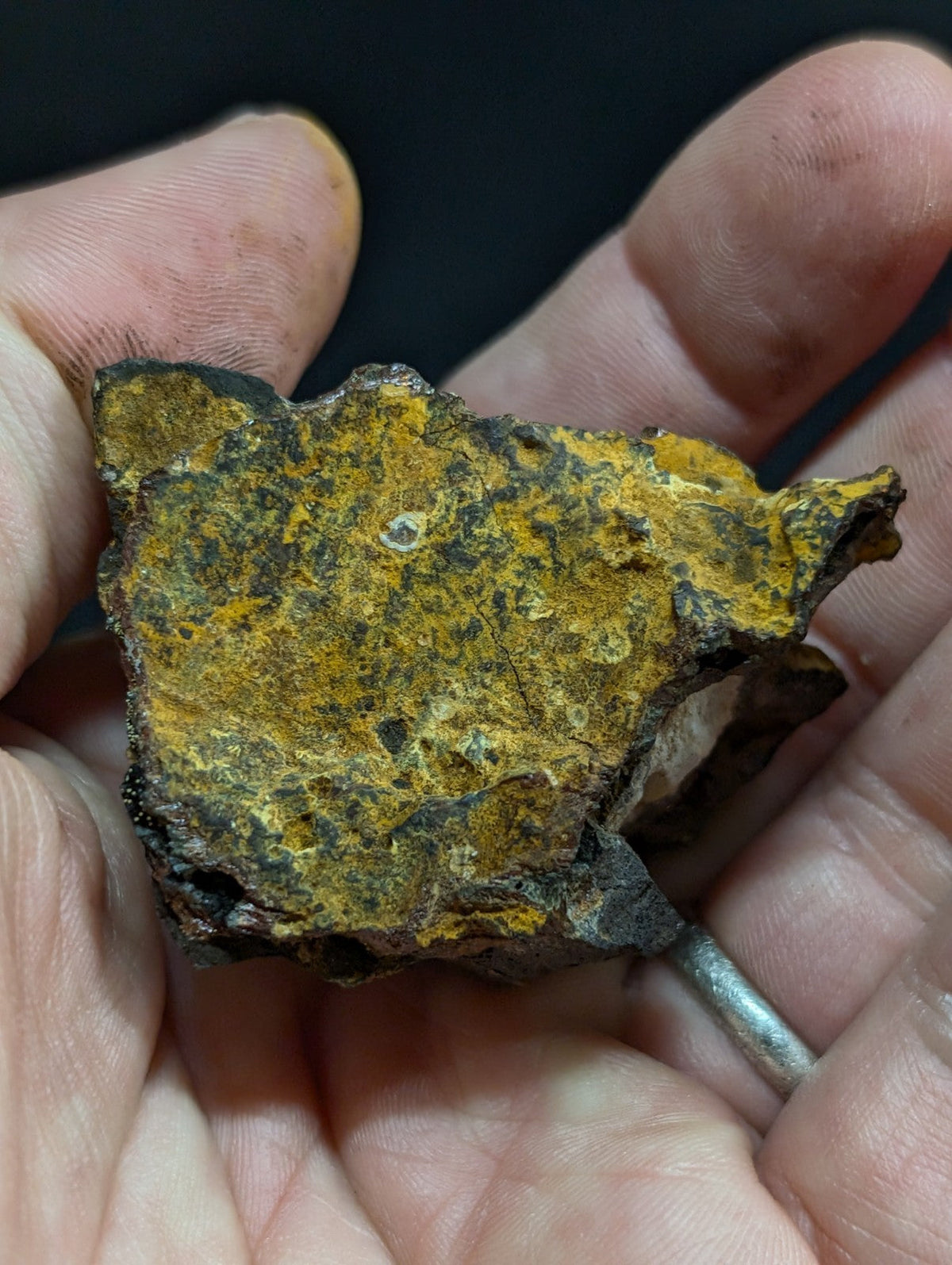 A rugged, irregularly shaped piece of iron meteorite with a striking yellowish-orange rusted surface and dark metallic patches.