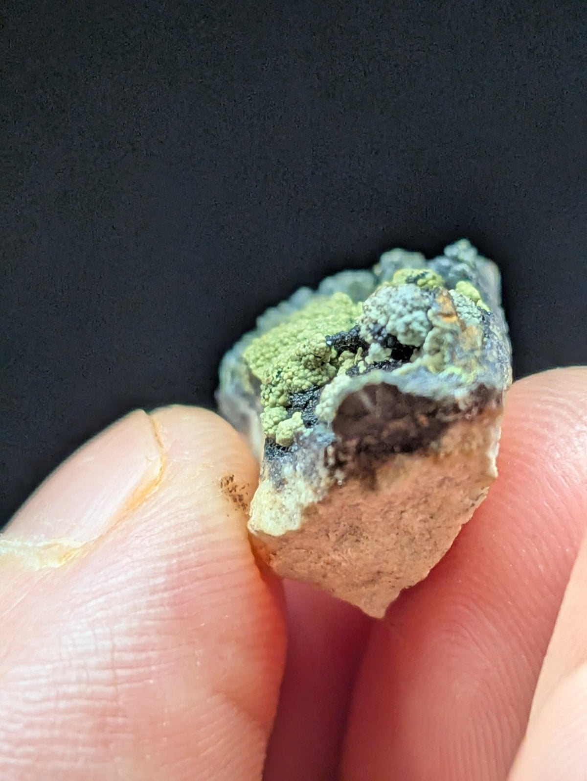 A rough, irregularly shaped mineral specimen with patches of vibrant green patina over a darker base and lighter tan crust.