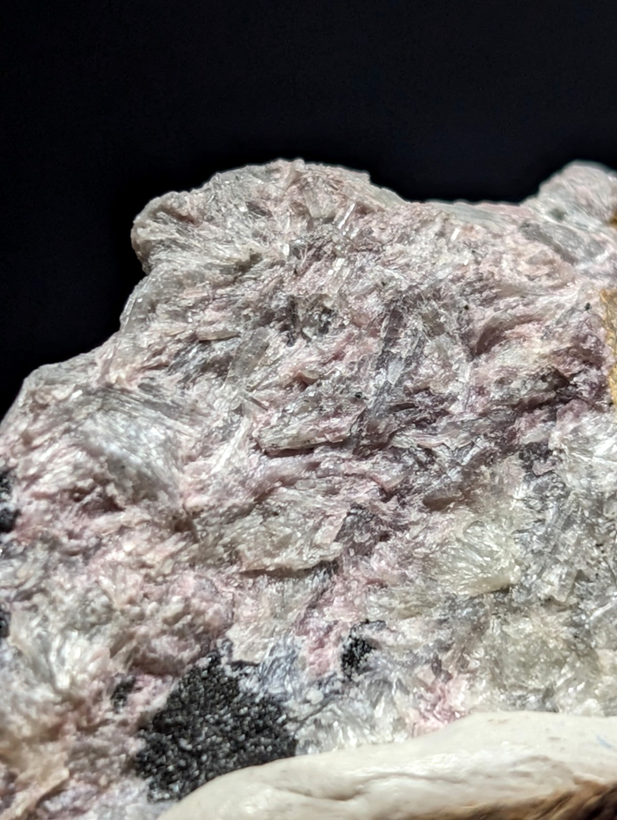 A rough, naturally occurring mineral specimen with a textured surface displaying pinkish and gray hues interspersed with translucent crystalline formations.