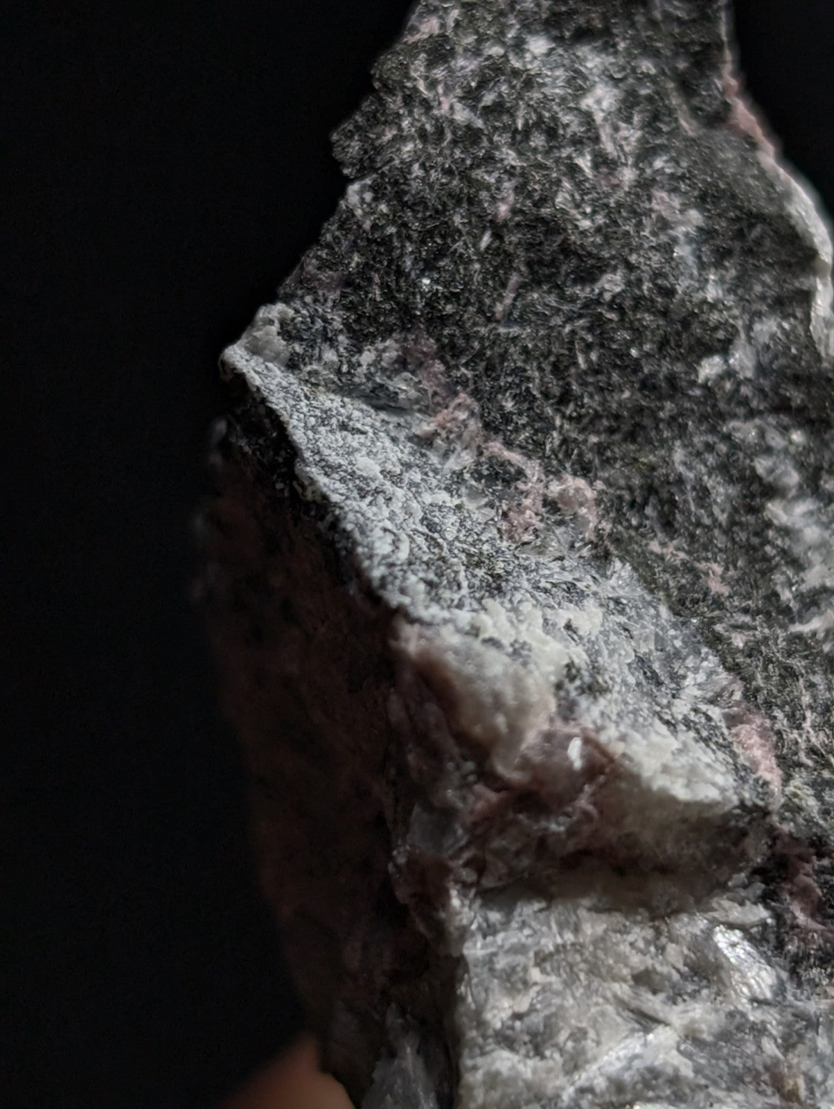 A rugged, naturally textured rock with a mottled pattern of dark gray and white speckles.