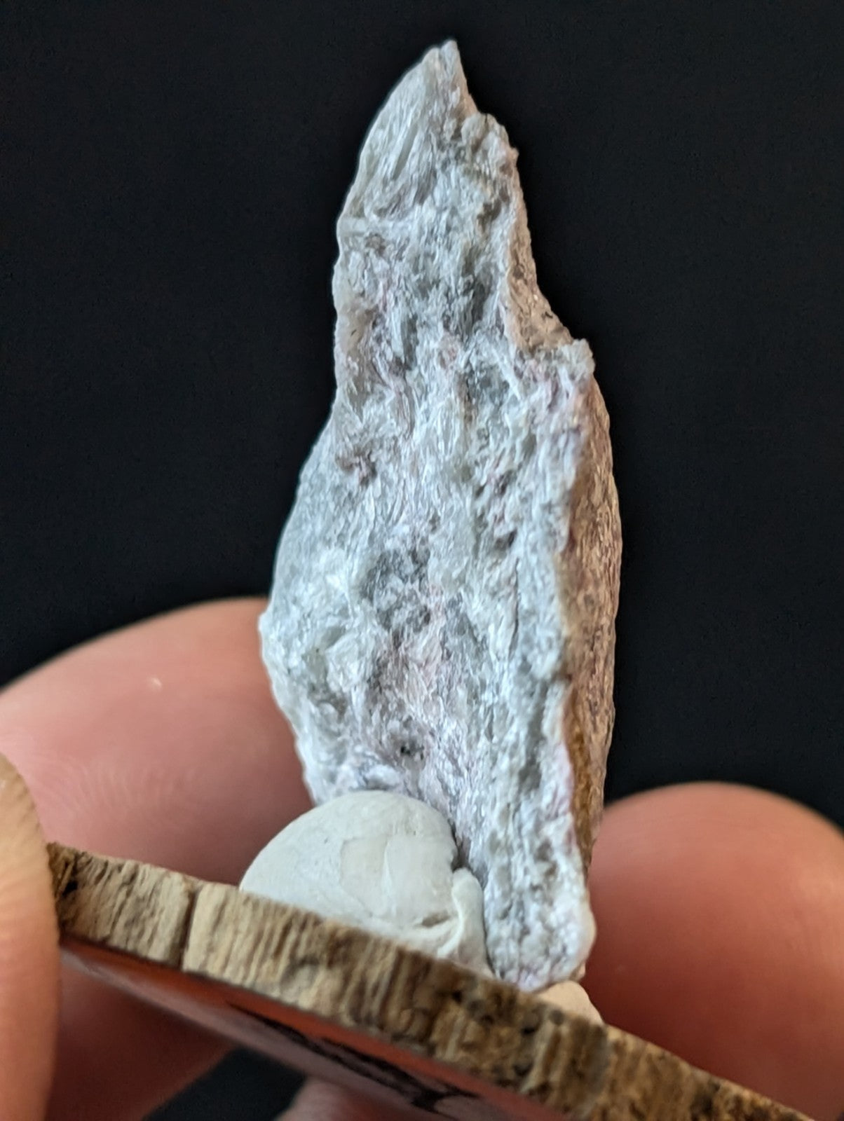 A gray, textured mineral specimen with a rough, uneven surface and subtle white veining.
