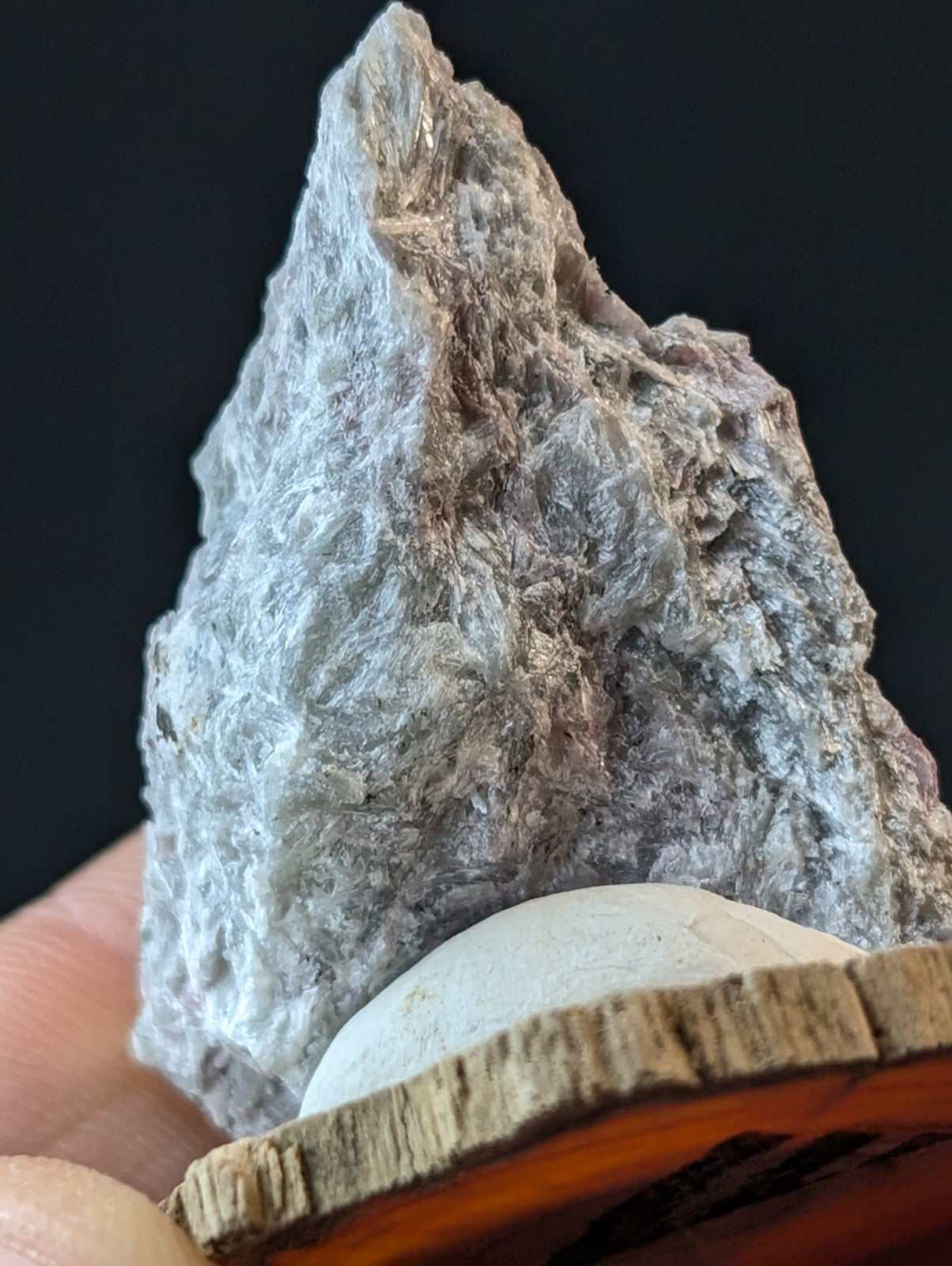 A textured, grayish-white mineral specimen with subtle brown veining and a rough, crystalline surface.