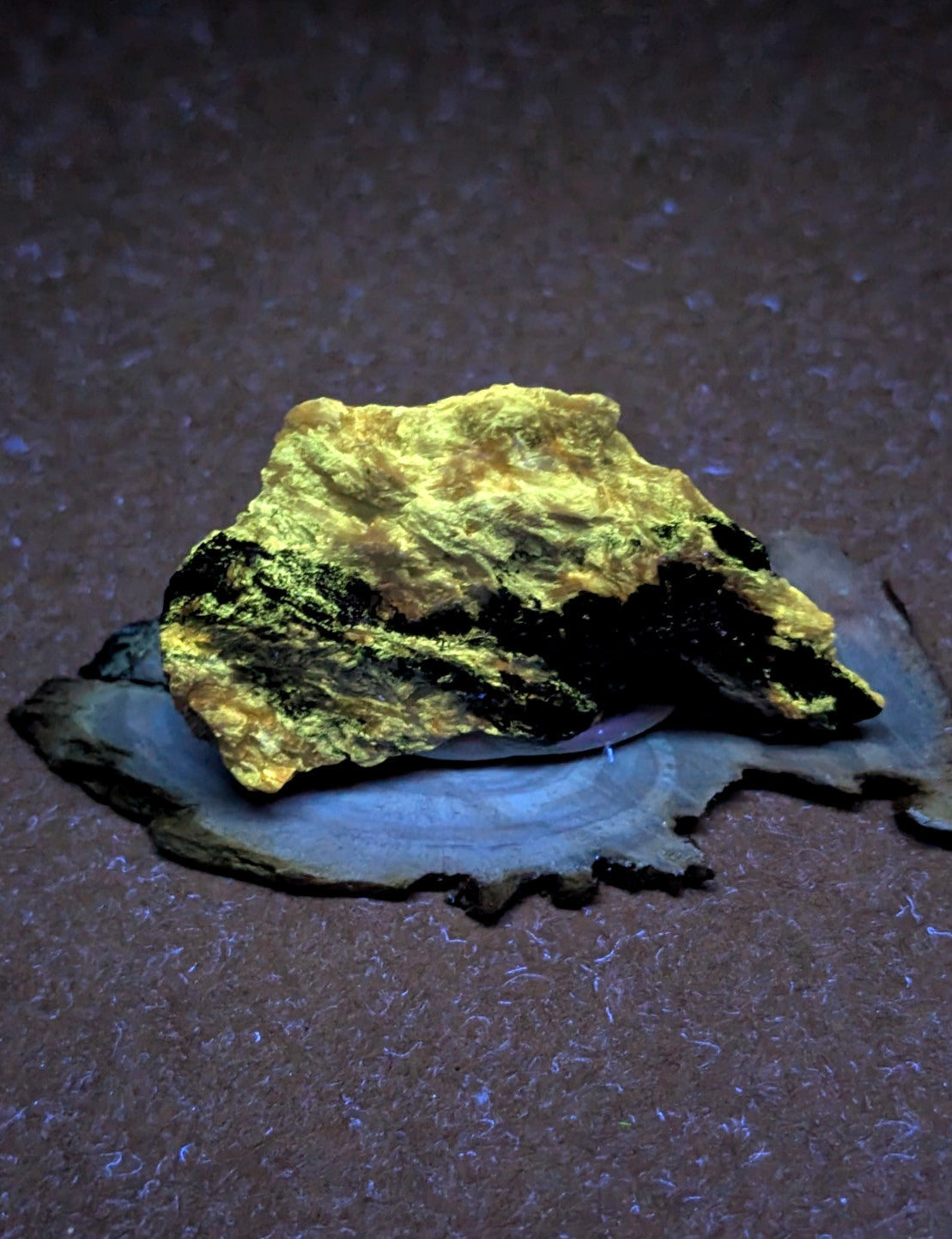 A chunky, naturally occurring gold specimen with a rough, irregular surface and patches of dark mineral matrix.