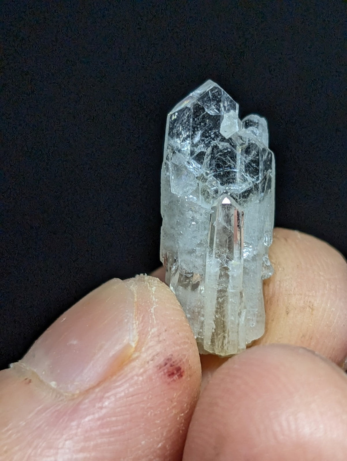 A translucent, clear quartz crystal cluster with a pointed tip and visible internal fractures.