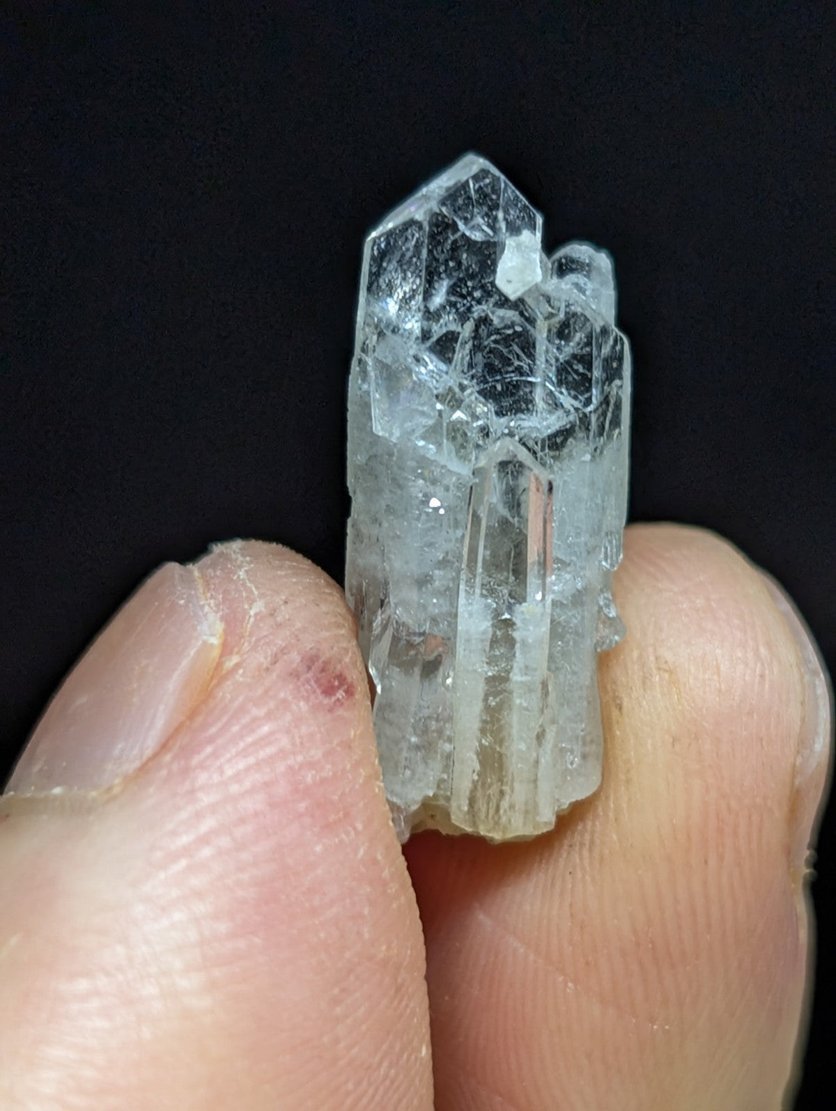 A translucent, clear quartz crystal cluster with visible internal inclusions and a faceted top.