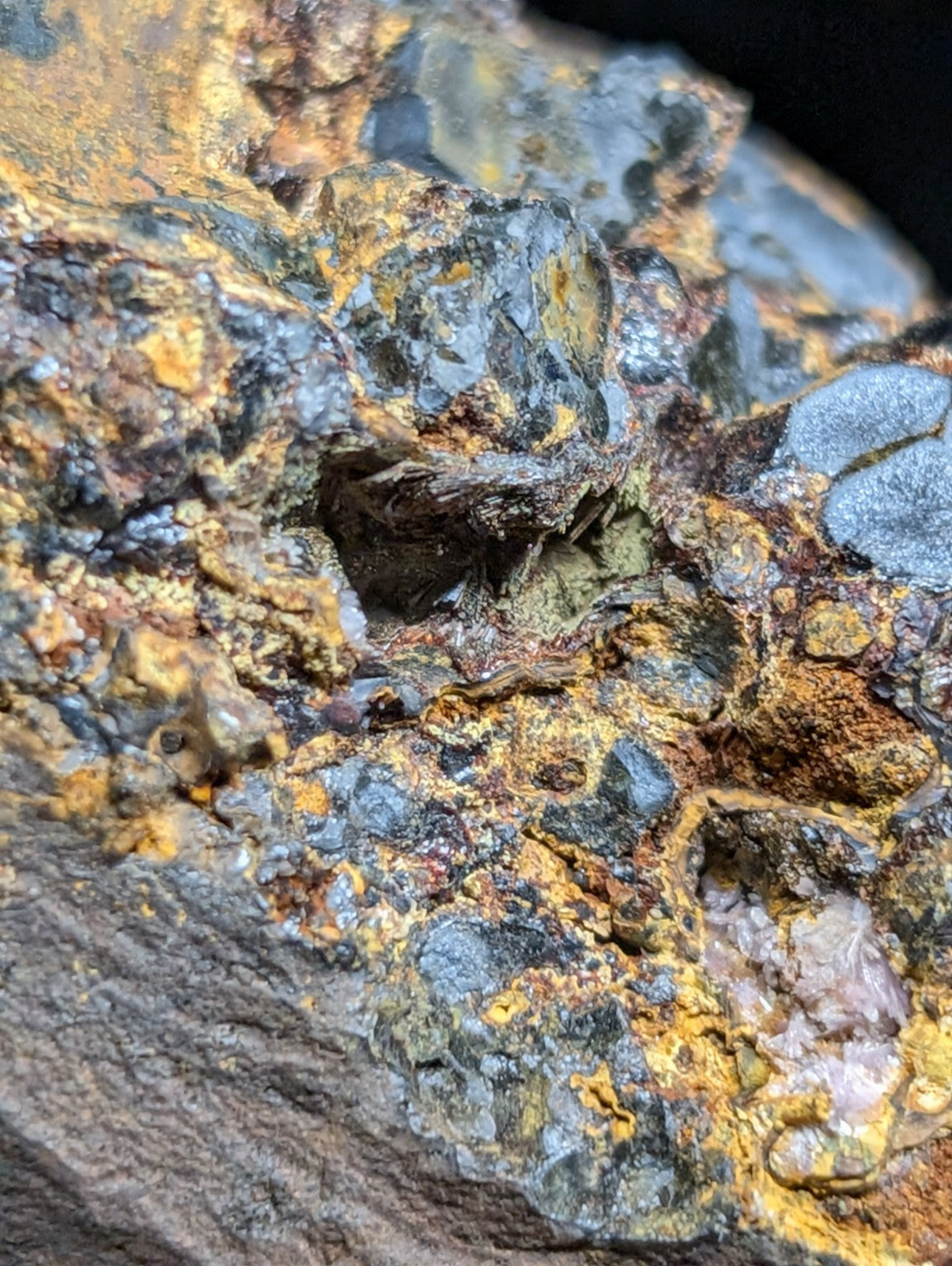 A rugged, multi-colored mineral specimen featuring patches of vibrant yellow and deep blue-gray with hints of rust-brown.