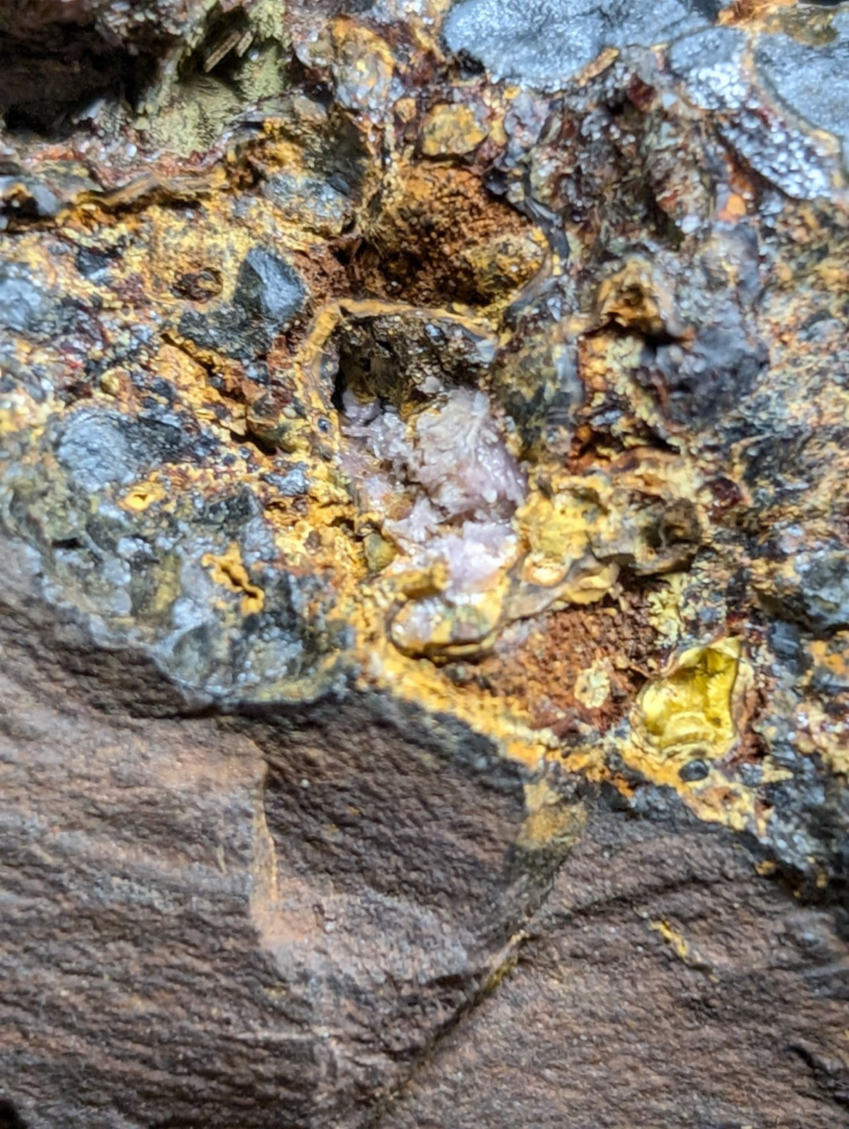 A rugged, textured rock surface with patches of vibrant yellow and dark gray mineral deposits.