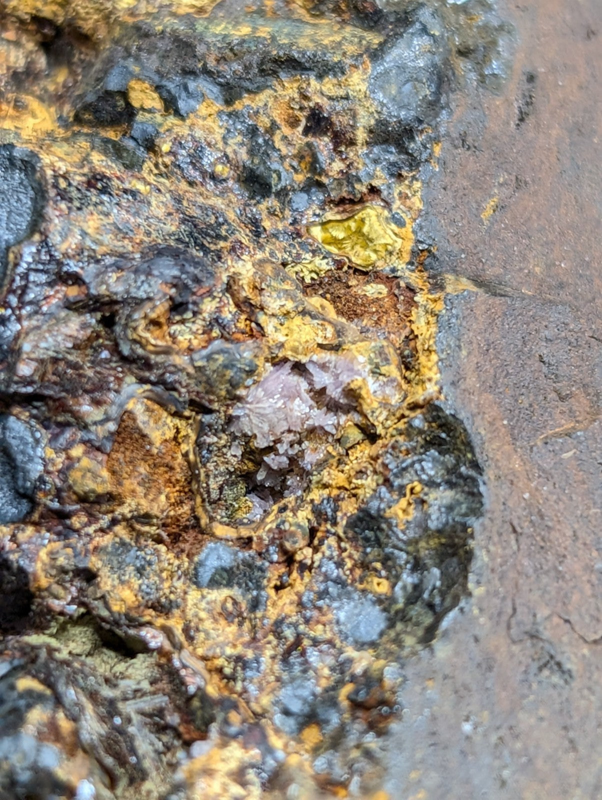 A weathered, rust-speckled metal surface with patches of yellowish corrosion and darkened areas.