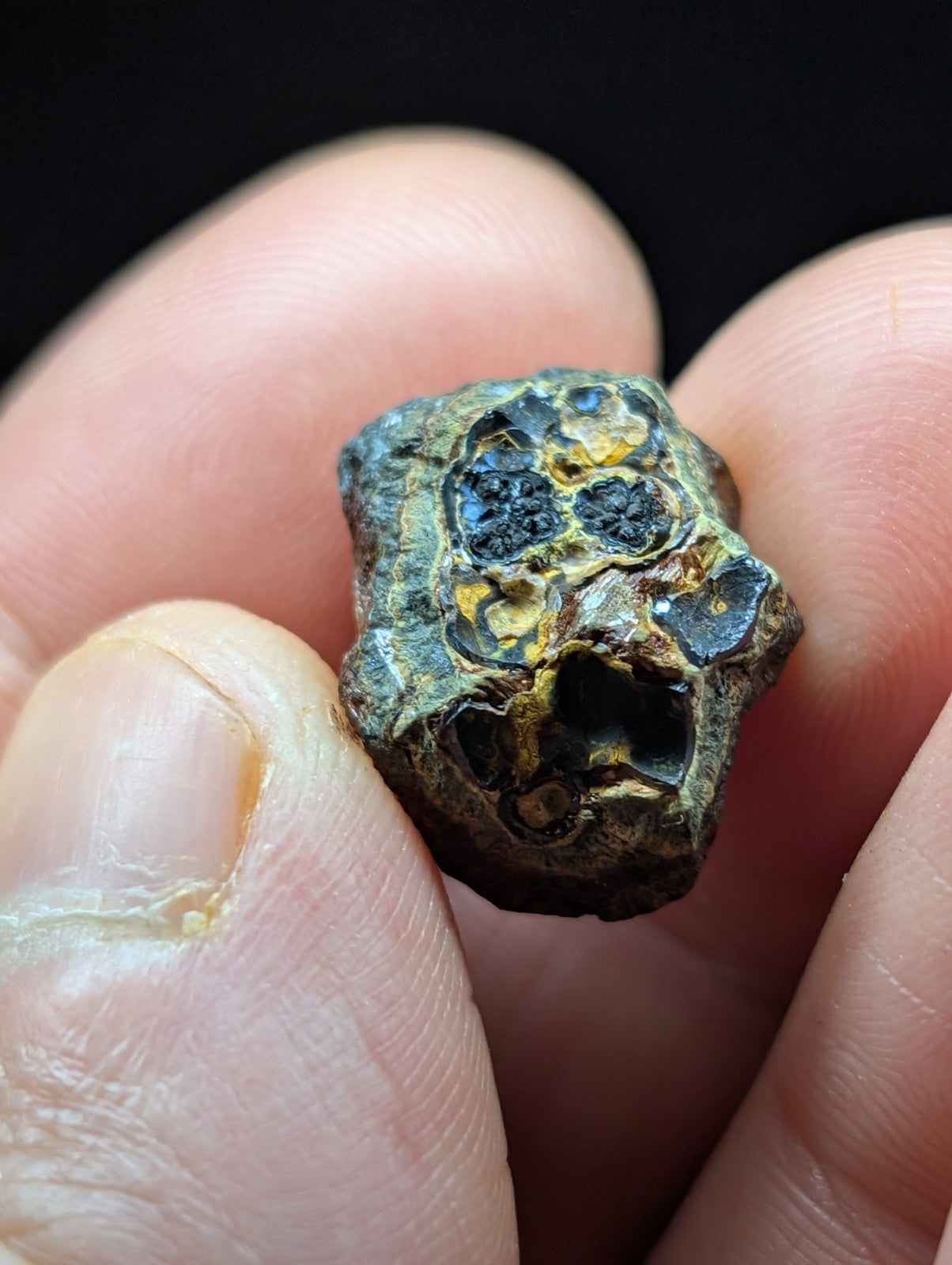 A rugged, irregularly shaped meteorite with a dark greenish-blue patina and embedded golden-yellow inclusions.