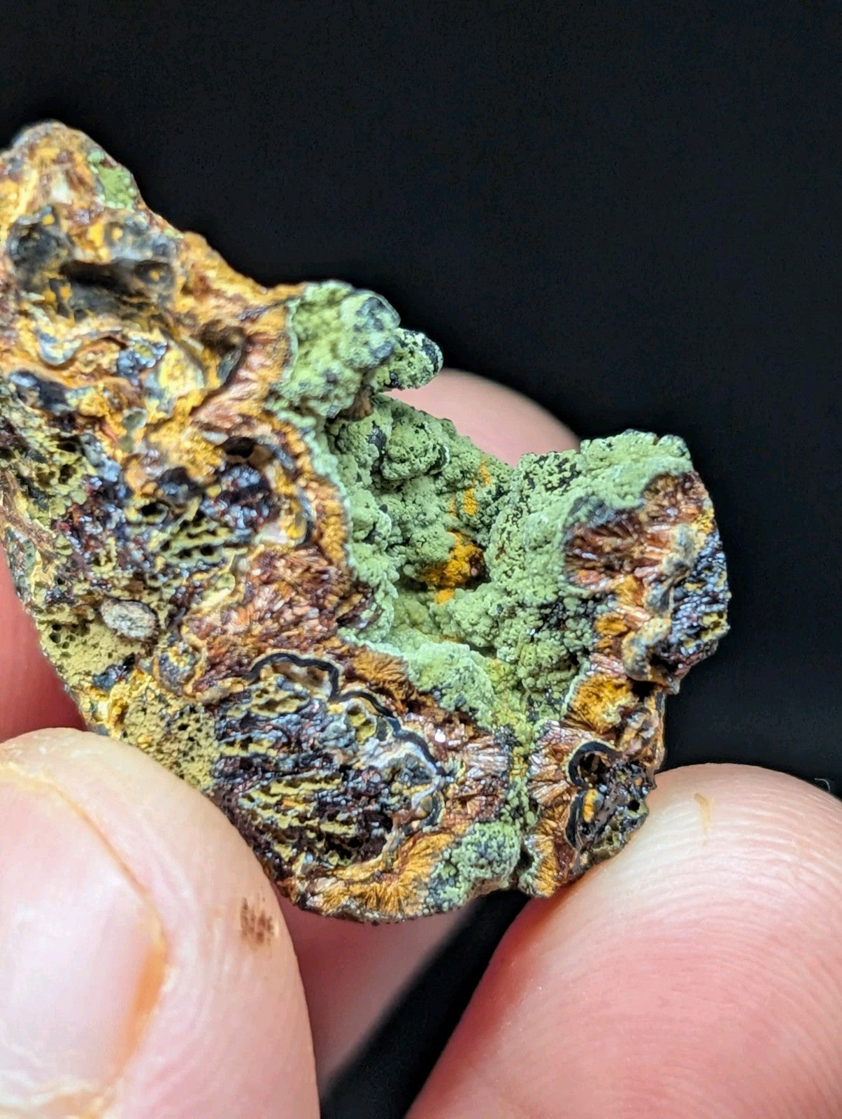 A rugged, irregularly shaped mineral specimen with a textured surface featuring patches of vibrant green moss-like growth over exposed brown and yellowish rock.