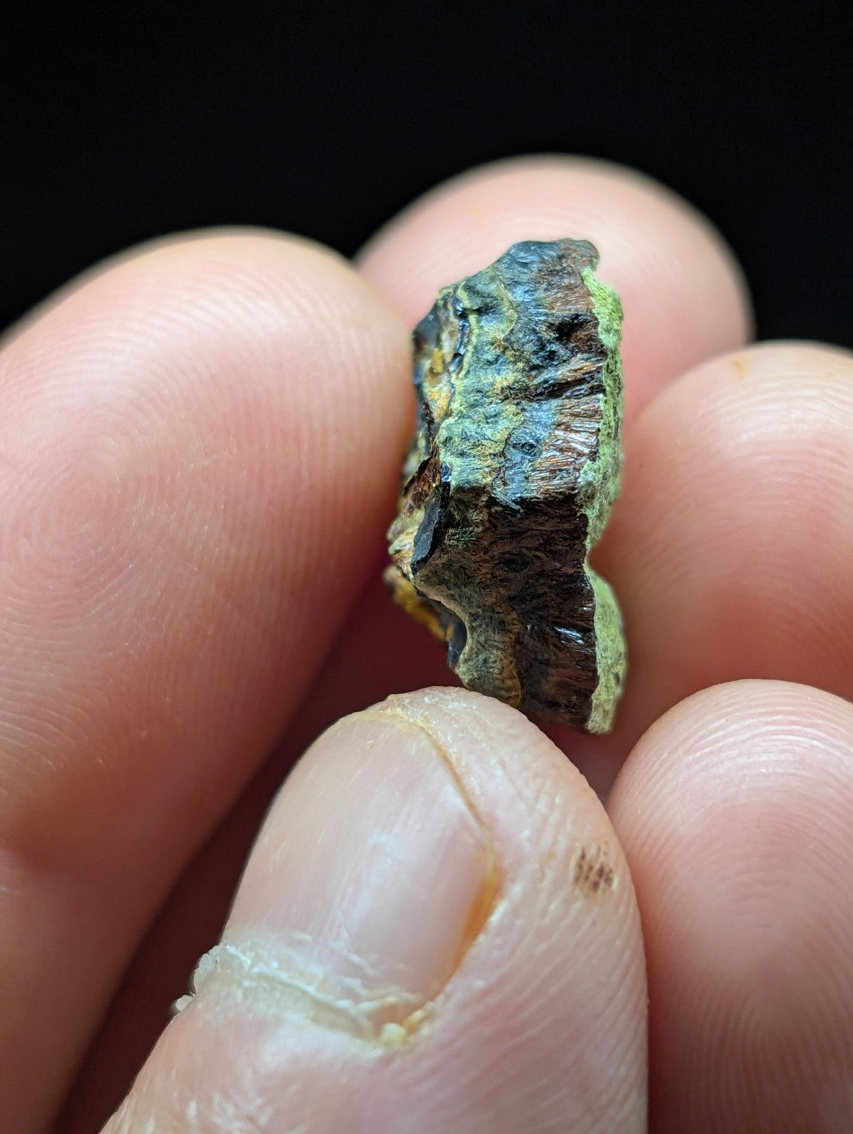 A weathered, irregularly shaped piece of mineral with a greenish-blue patina and dark brown core.