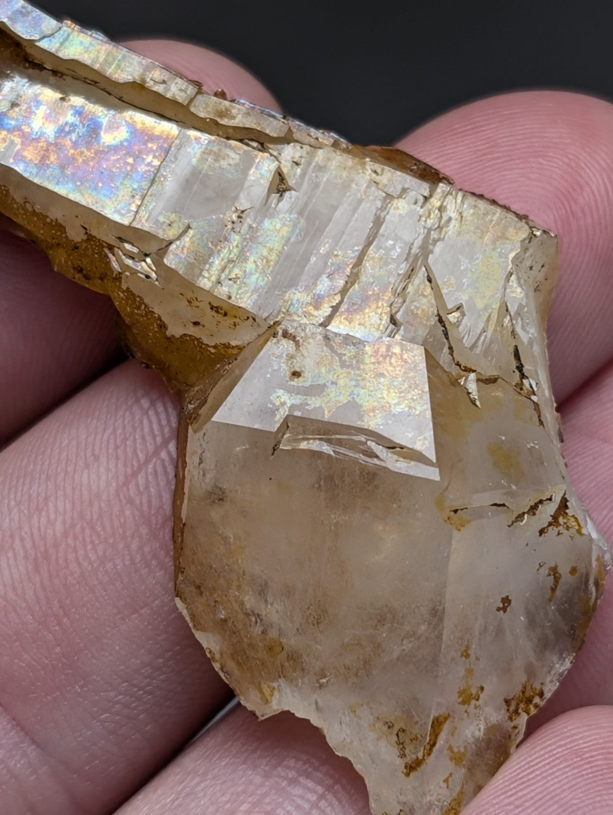 A translucent golden-brown quartz crystal with iridescent facets and rough surface from Garland County Arkansas