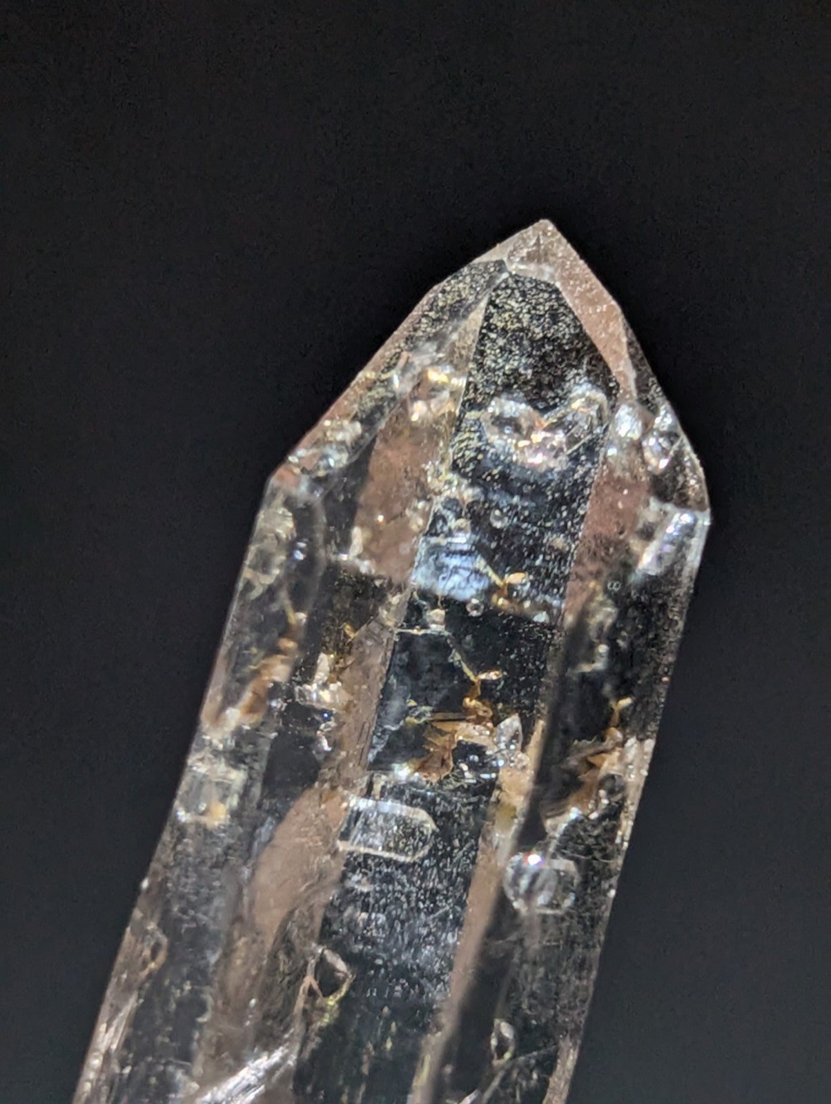 A clear quartz crystal with a pointed tip and visible internal inclusions.