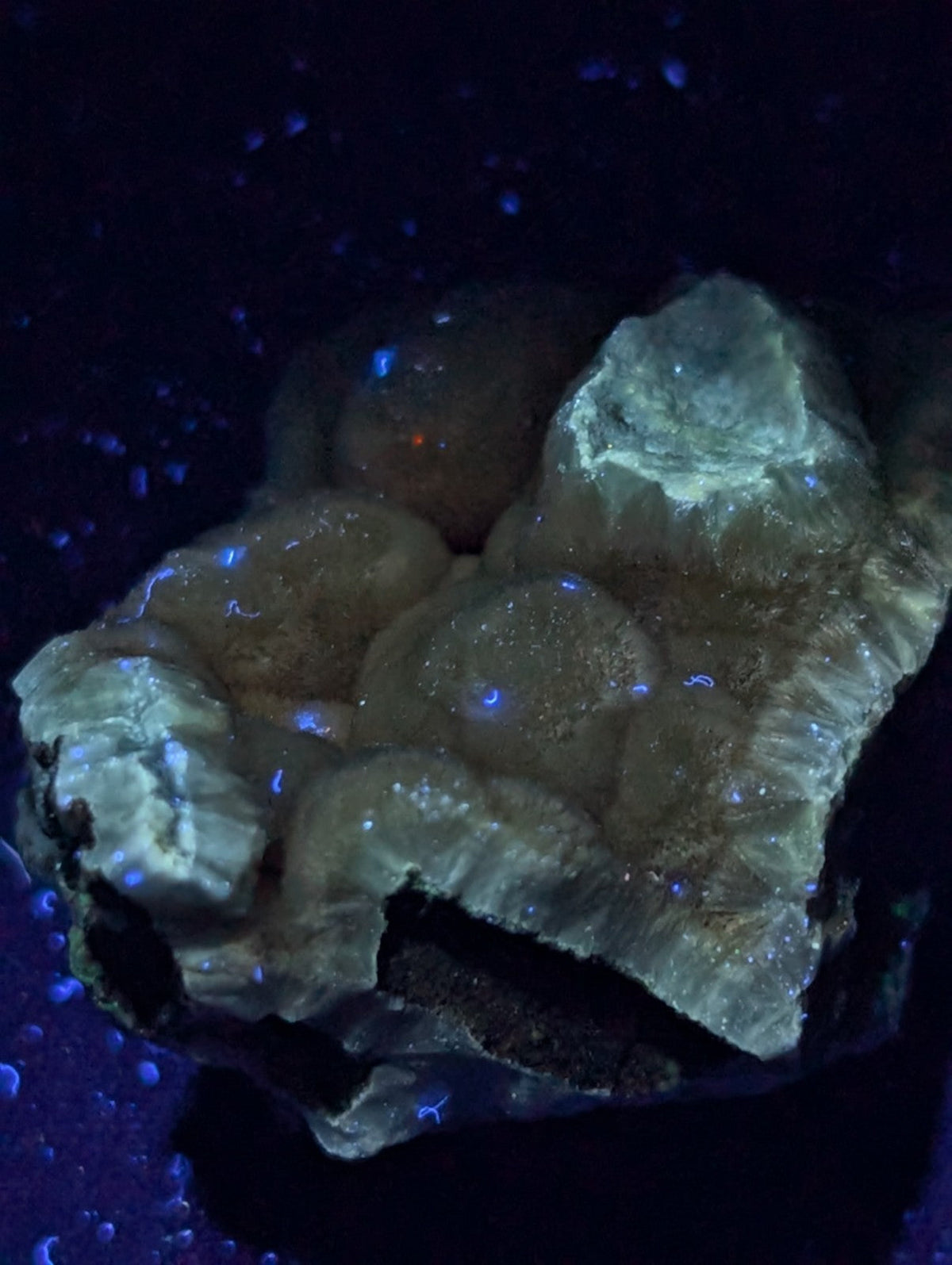 A glowing blue mineral specimen with a rough, textured surface and translucent patches.