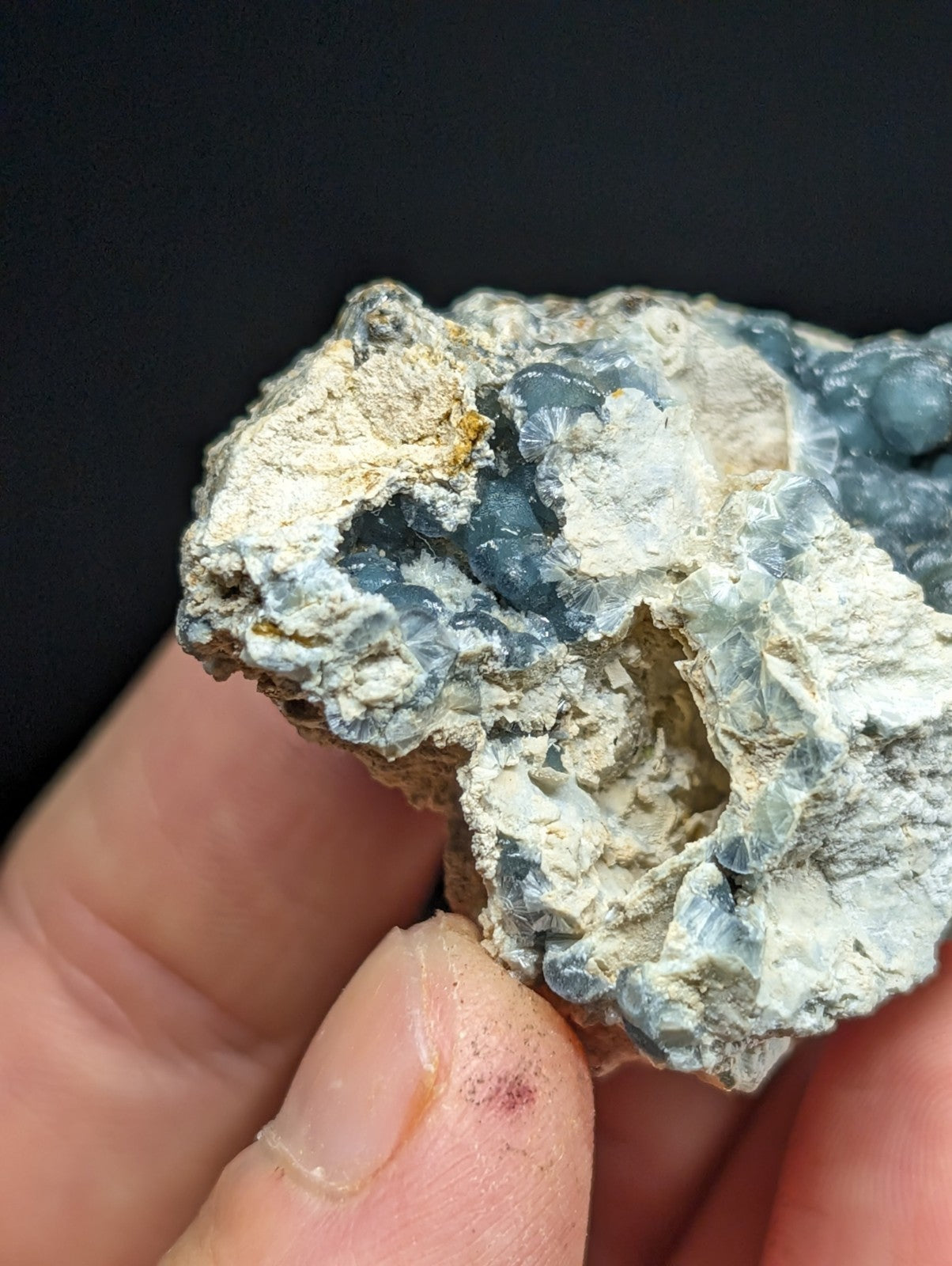 A rough, irregularly shaped mineral specimen featuring translucent blue and white crystalline formations embedded in a pale matrix.