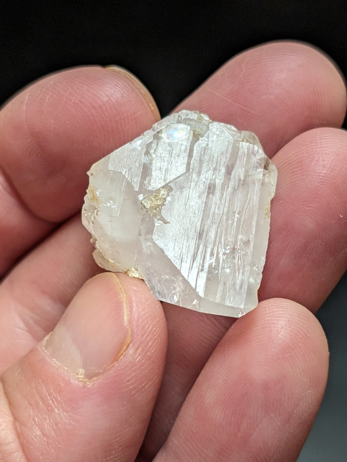 A translucent, clear quartz crystal with visible internal striations and a rough, natural edge.