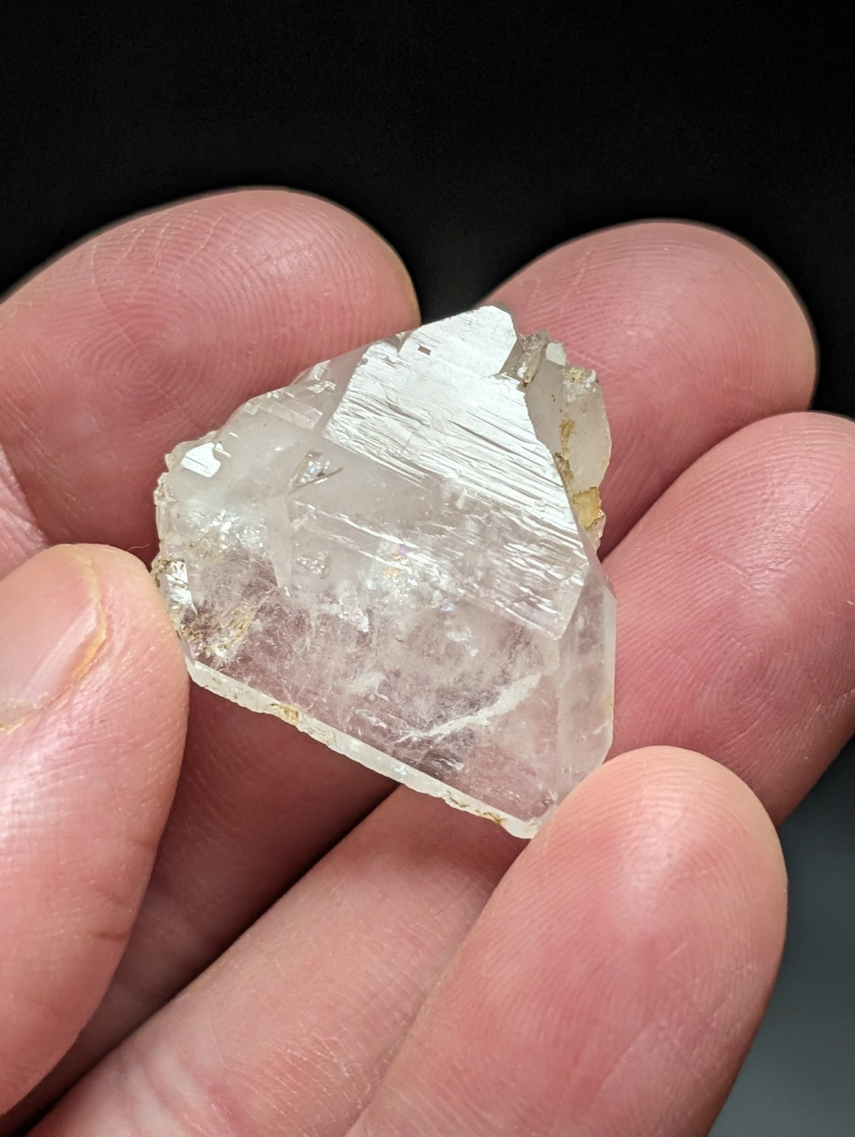 A translucent, clear quartz crystal with visible internal striations and a rough, natural edge.