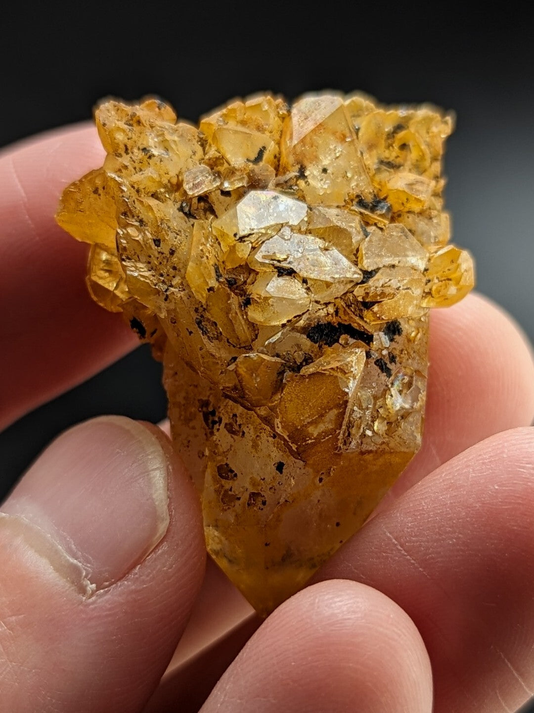 A translucent golden-yellow crystal cluster with sharp, faceted points and embedded dark inclusions.