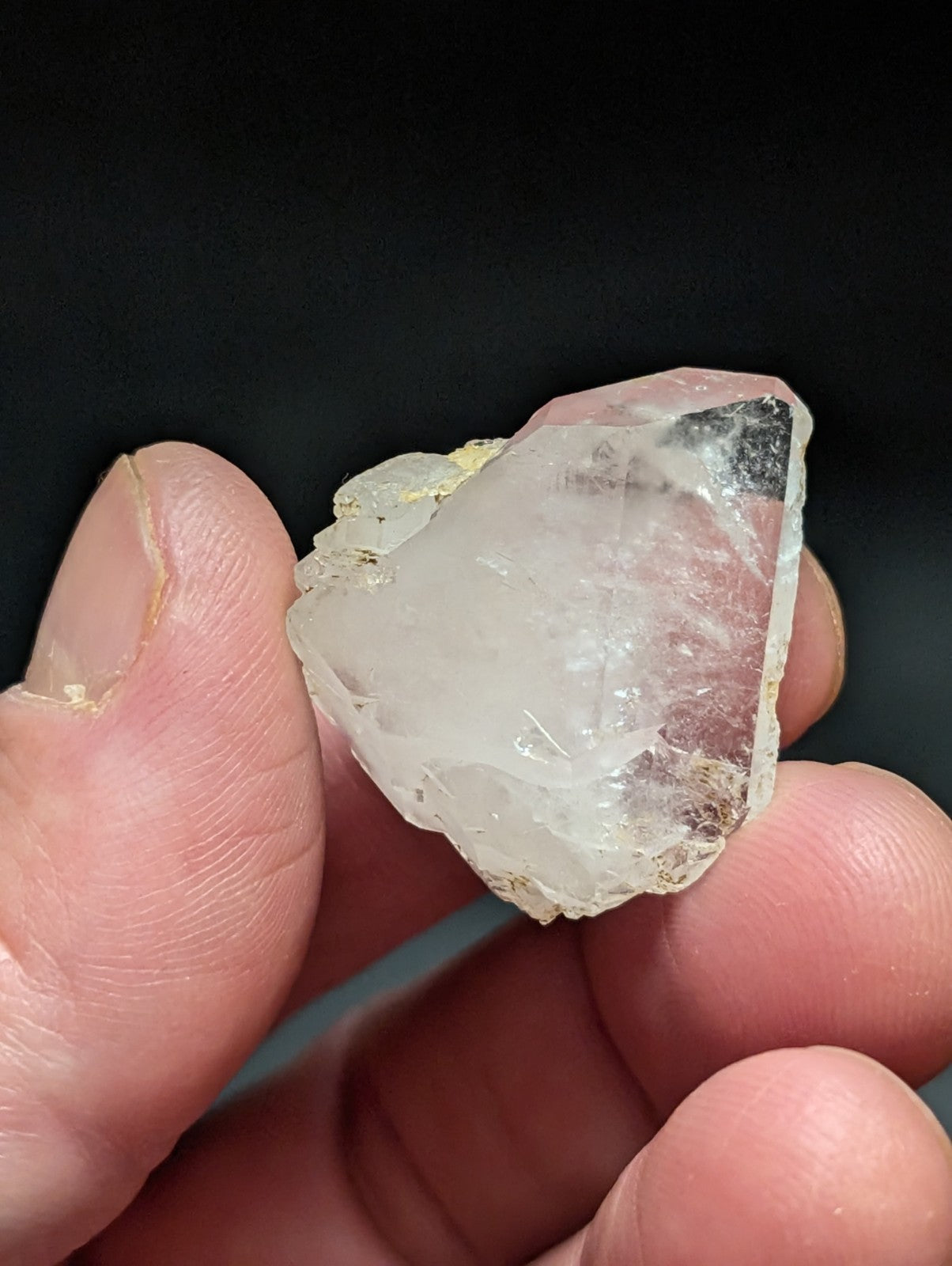 A translucent, irregularly shaped quartz crystal with a slightly cloudy white interior and dark mineral inclusions along its edges.