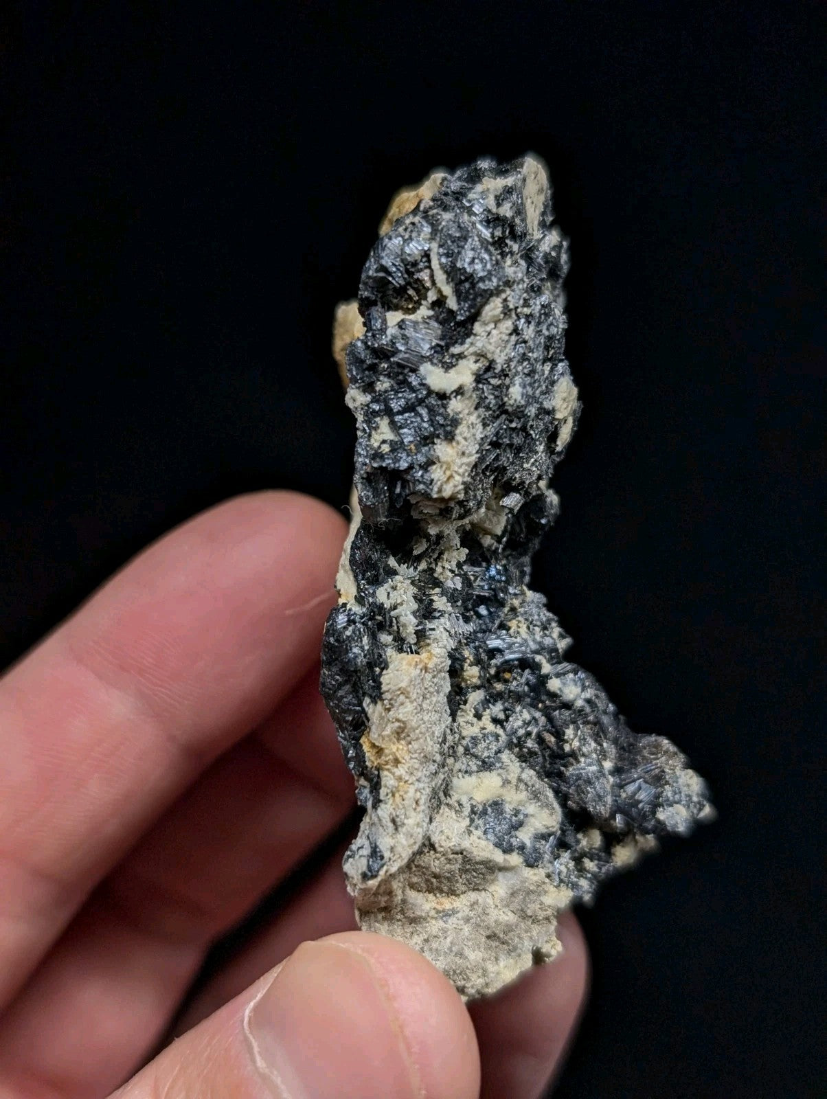 A rugged, irregularly shaped mineral specimen with a mottled surface of dark gray and light beige patches.