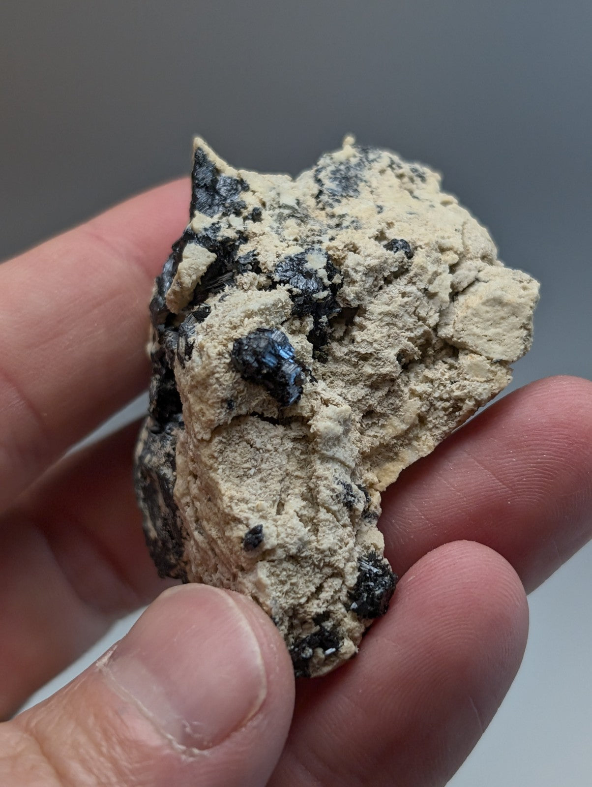 A rough light beige rutile in matrix cluster with dark blue and black mineral inclusions from magnet cove arkansas