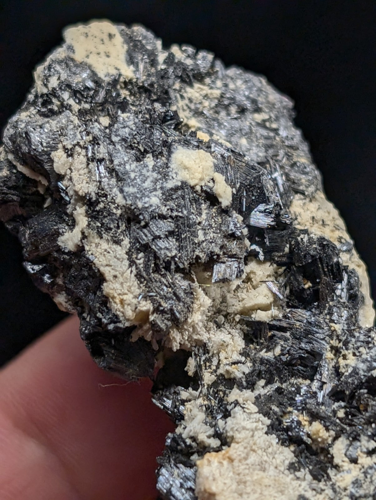 A rugged, naturally occurring mineral specimen featuring a striking contrast between dark, metallic-looking crystals and lighter, creamy-colored matrix material.