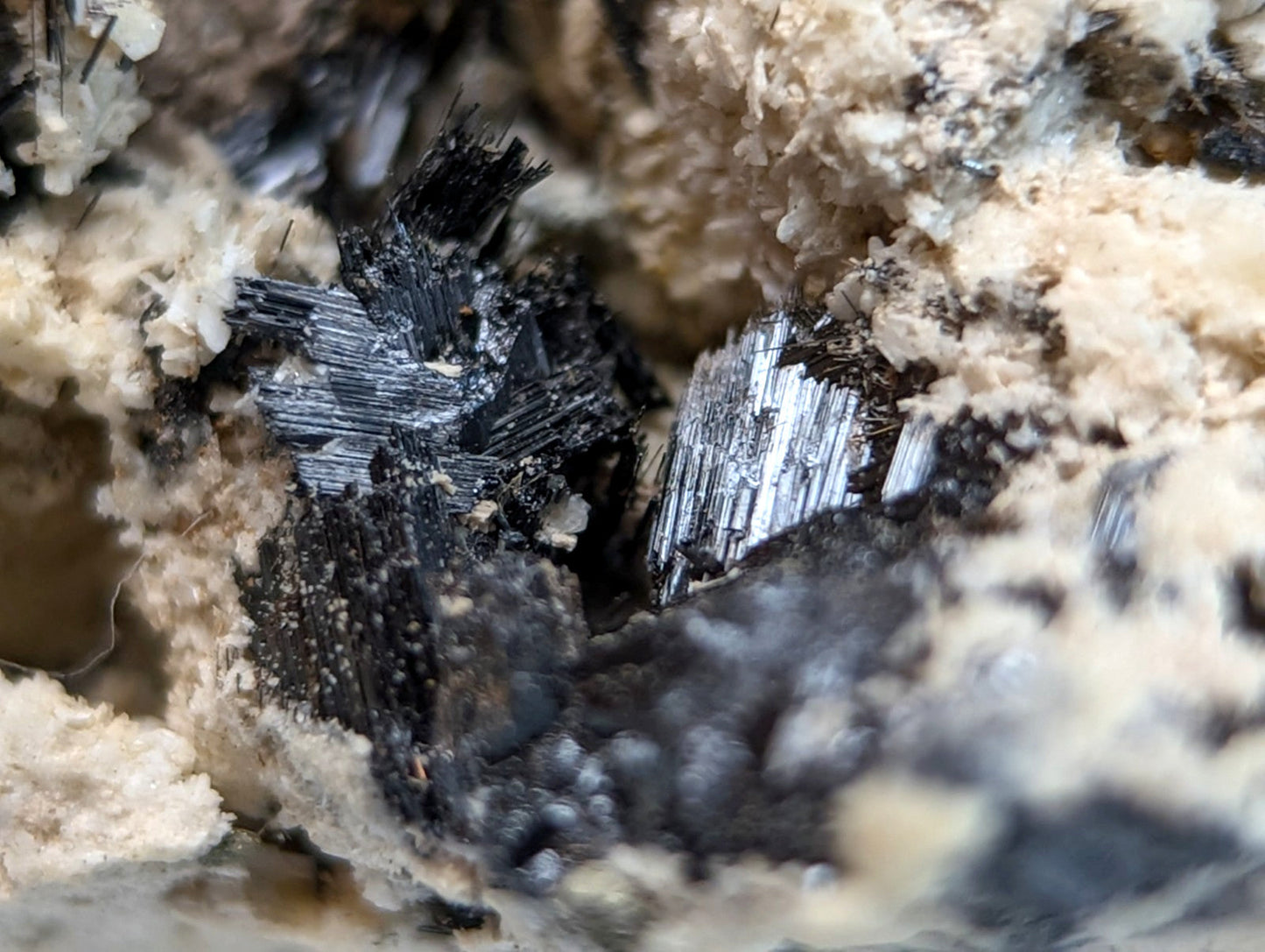Black and silver metallic rutile crystals in light beige granular rock matrix from magnet cove arkansas super rare cluster