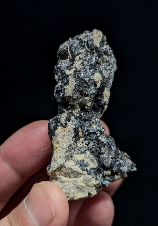 A rugged, irregularly shaped mineral specimen with a mottled surface of dark gray and light beige patches.