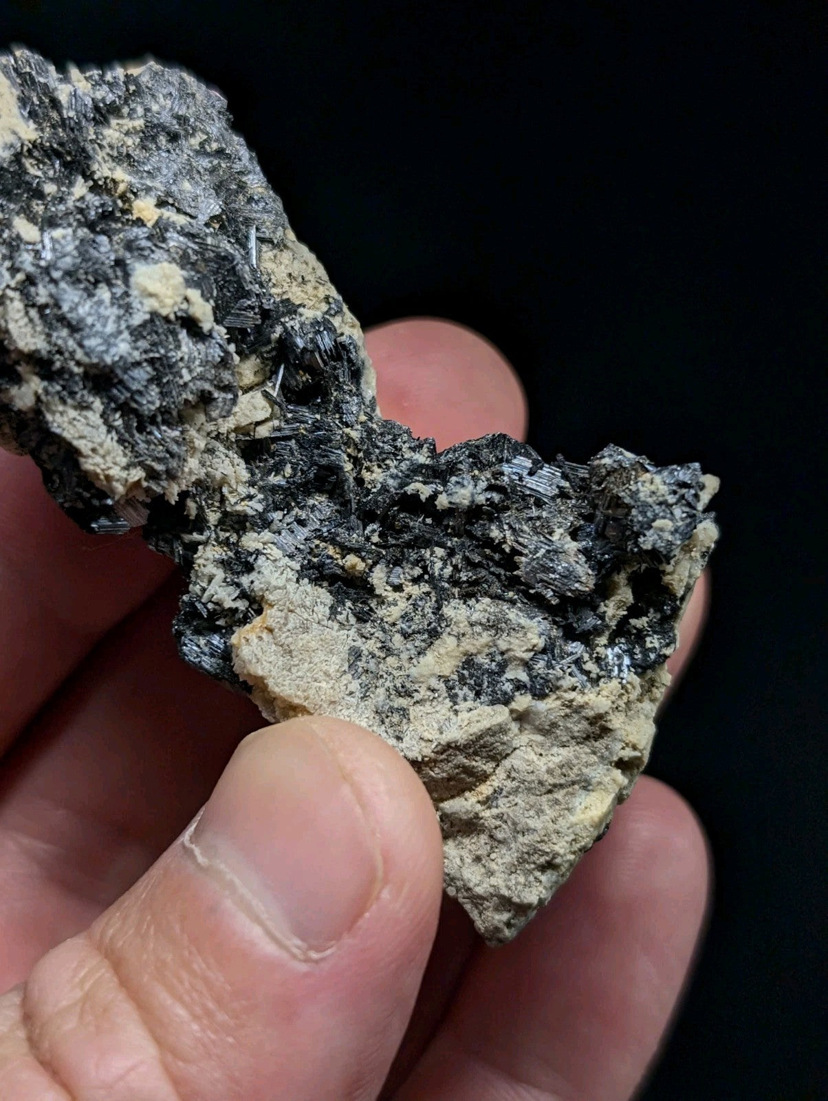 A rugged, irregularly shaped mineral specimen with a dark gray and black matrix interspersed with lighter beige patches.