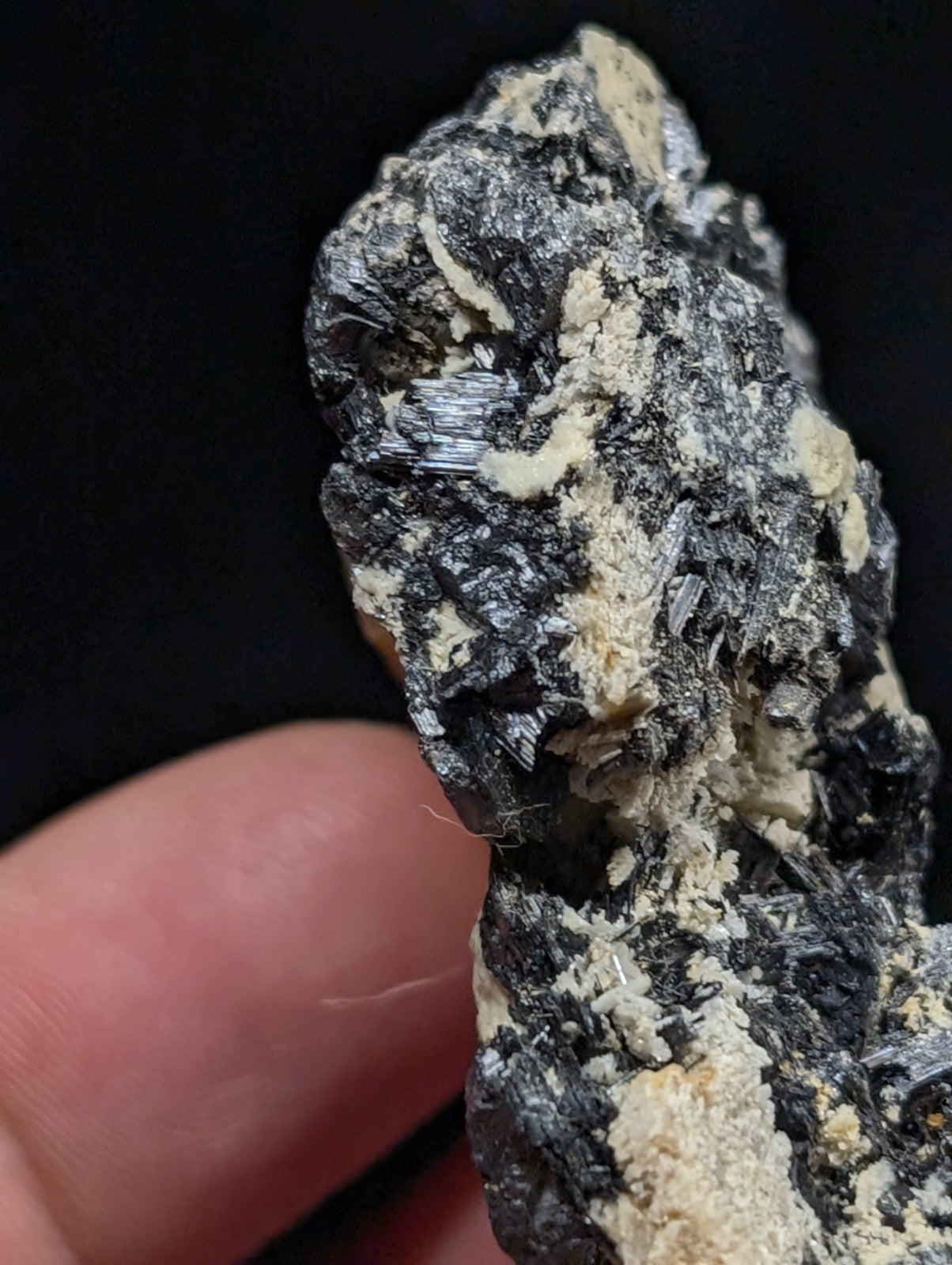 A rugged, irregularly shaped mineral specimen featuring a striking contrast between dark, metallic-looking crystals and lighter, creamy-colored matrix material.