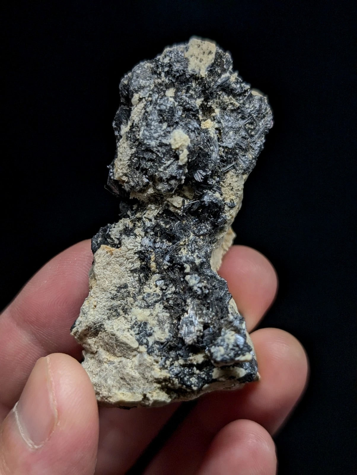 A rugged, irregularly shaped mineral specimen with a mottled surface of dark gray and light beige patches.