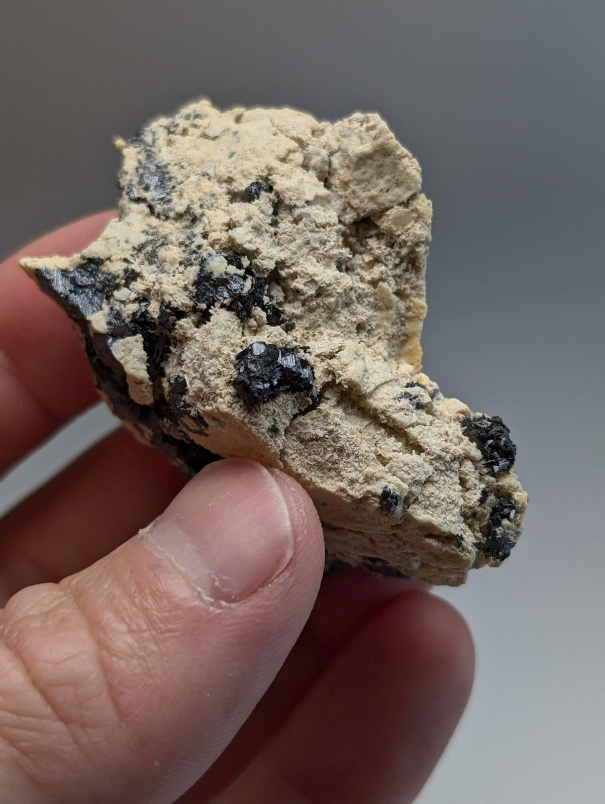 A rough beige rutile in matrix rock with scattered black mineral inclusions from magnet cove arkansas beautiful cluster