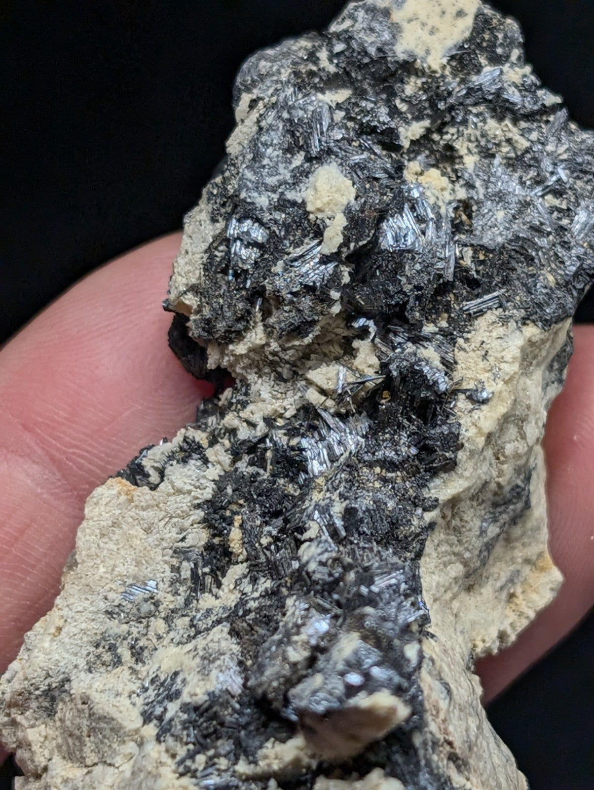 A rugged, irregularly shaped mineral specimen featuring a striking contrast between dark, metallic-looking crystals and lighter beige matrix material.