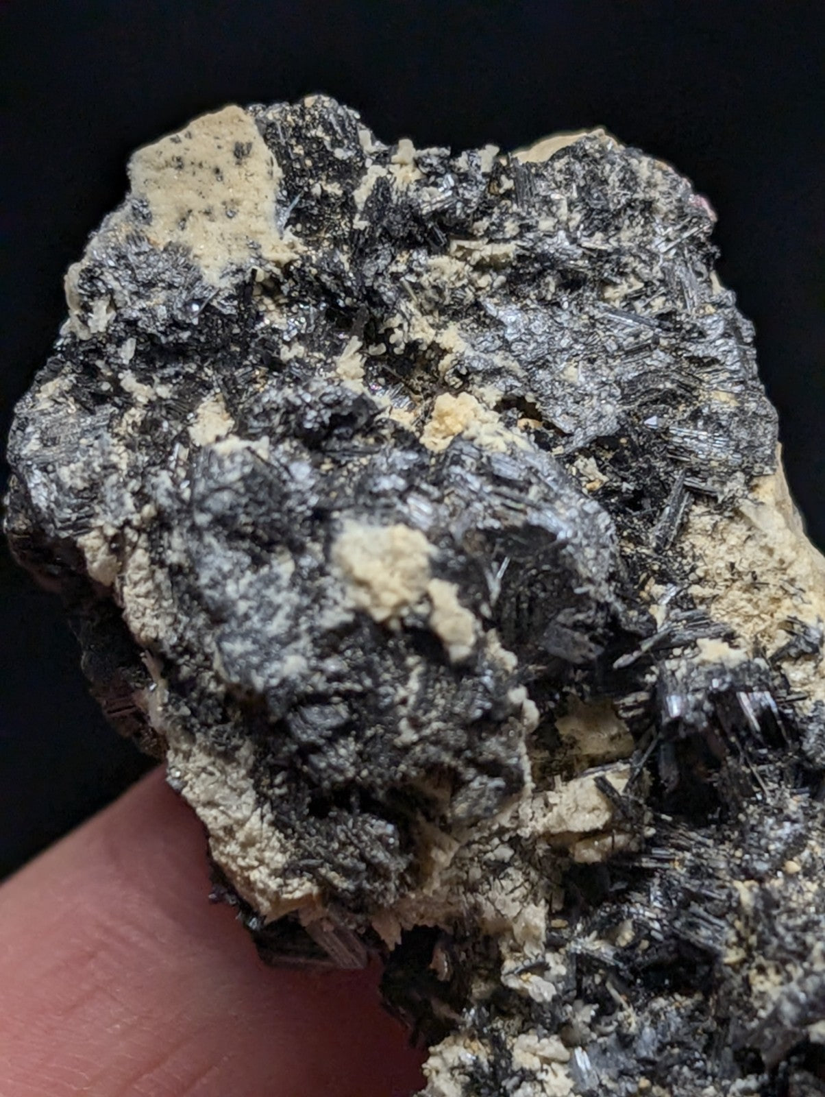 A rugged, naturally occurring mineral specimen featuring a striking contrast between dark, metallic-looking crystals and lighter, creamy matrix material.