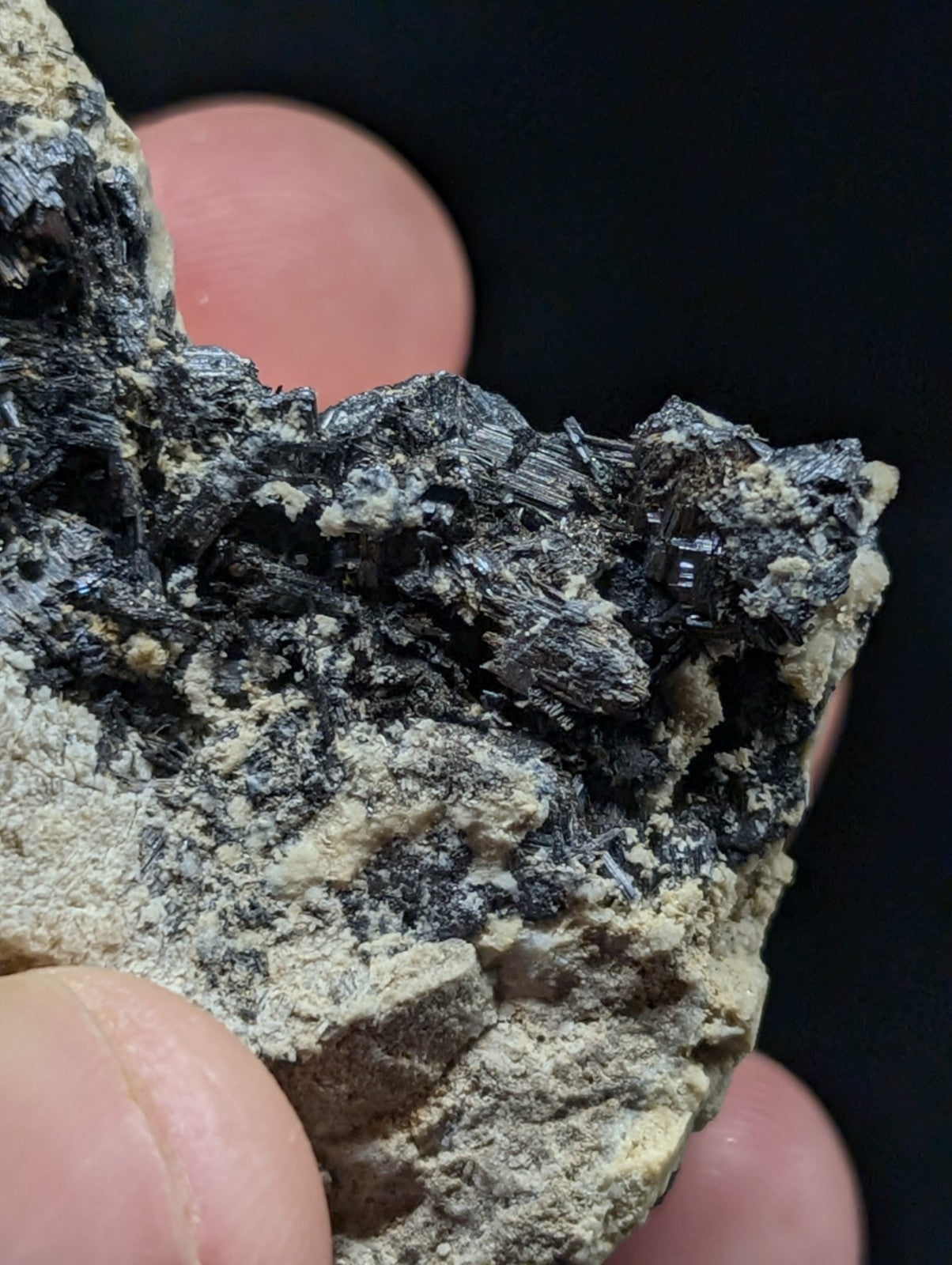 A dark, crystalline mineral specimen with sharp, angular facets and a rough, earthy matrix.