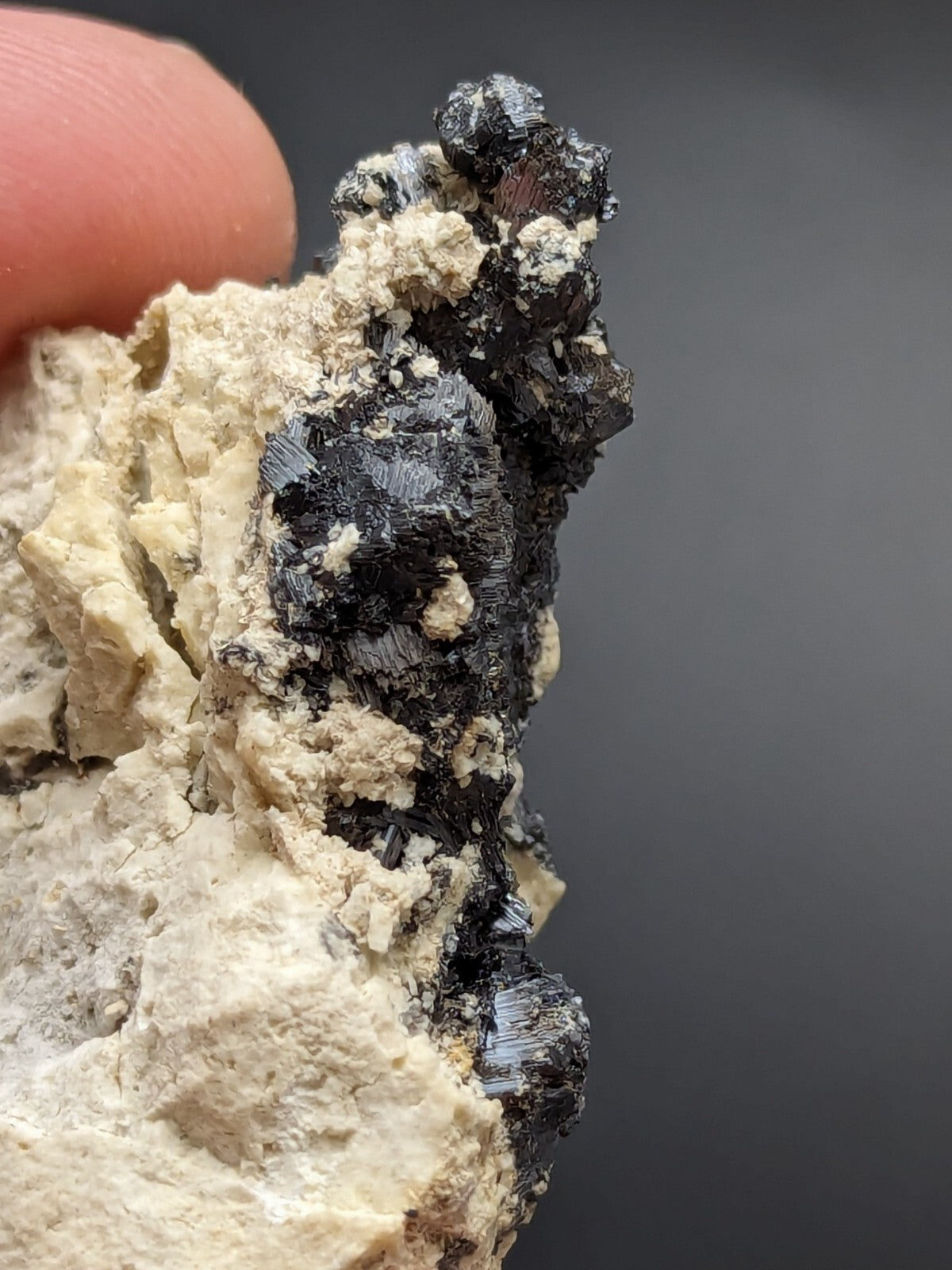 A dark, crystalline mineral specimen with a rough, textured surface and metallic sheen.