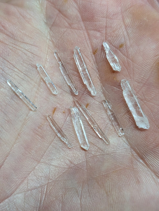 Clear quartz crystal points resting in an open palm.