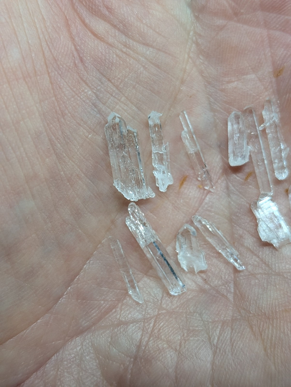 Clear quartz crystal fragments resting in an open palm.