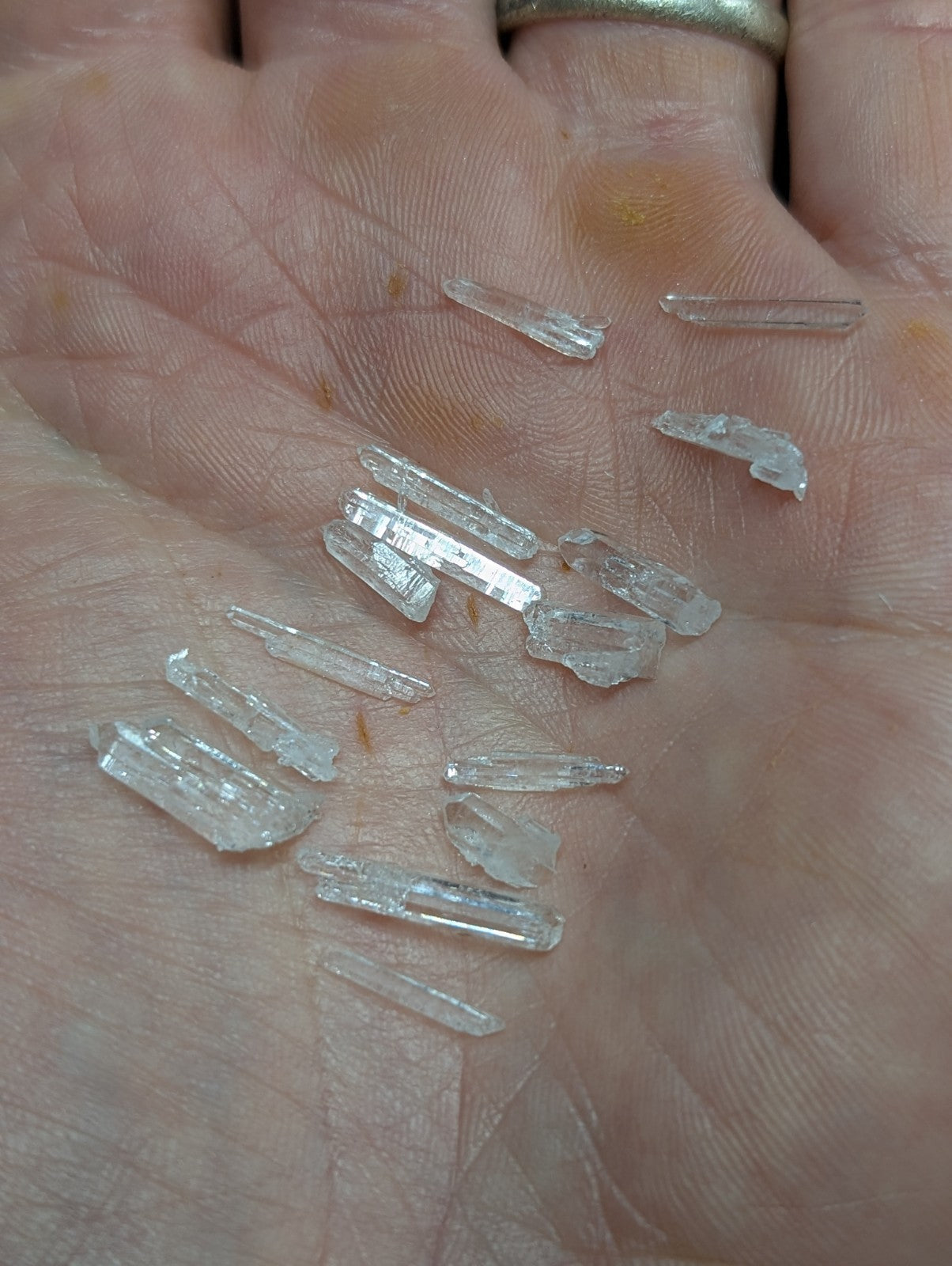 Clear quartz crystal fragments resting in an open palm.