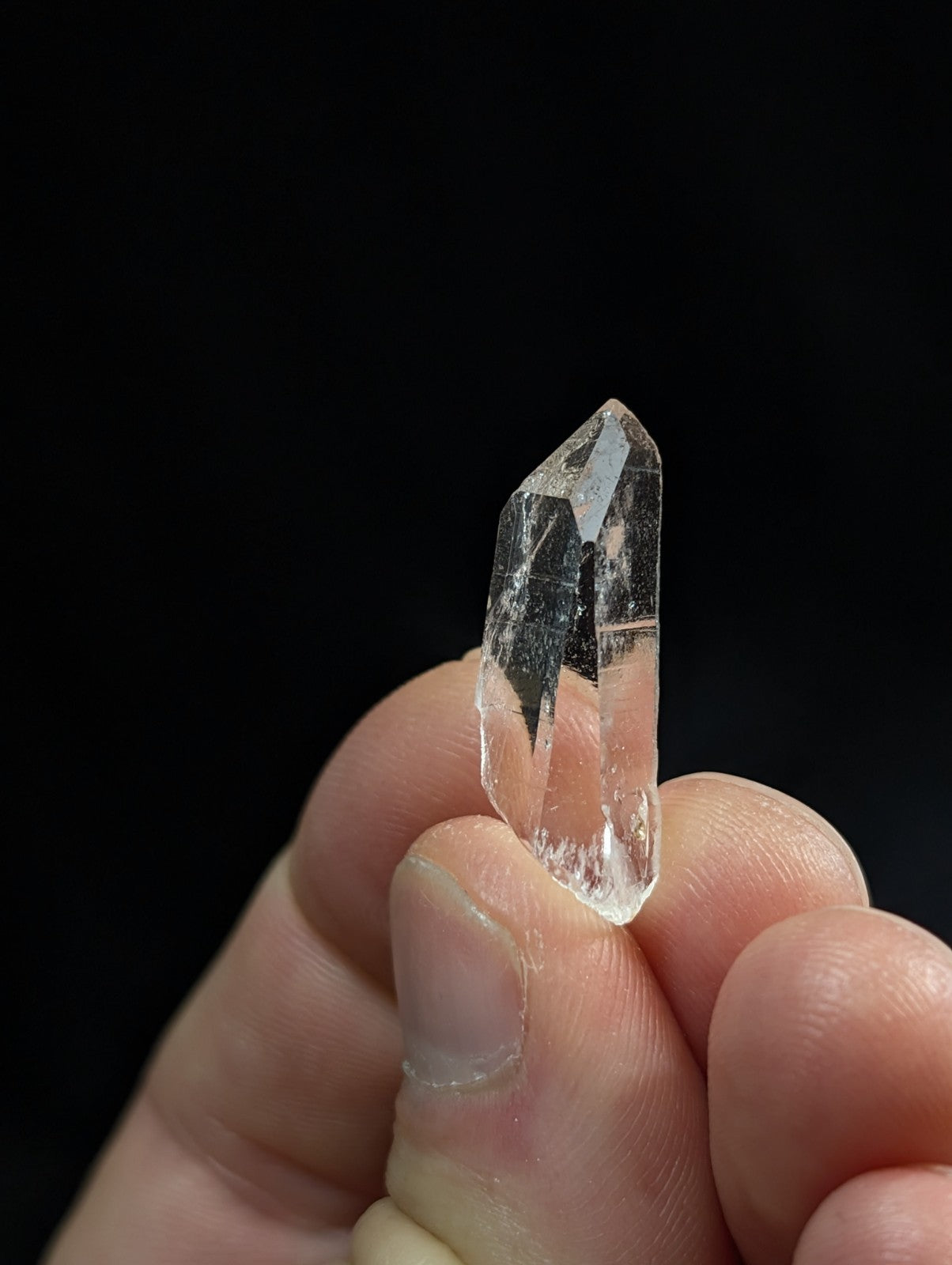 A clear, transparent quartz crystal with sharp facets and a pointed tip.